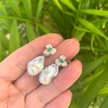 Charger l&#39;image dans la galerie, Emerald stud earrings with pearl drops held in hand against green leaf backdrop
