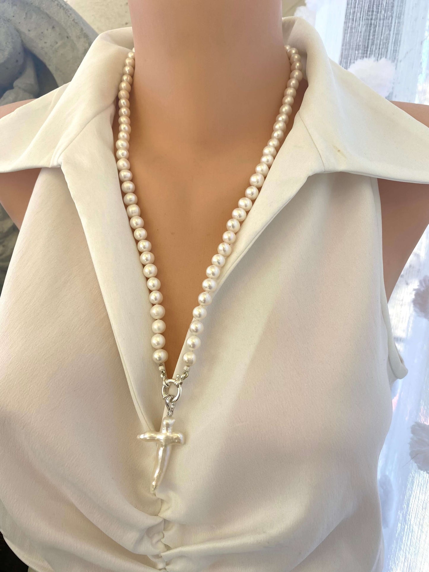 Baroque pearl cross pendant on long white pearl necklace, front view on mannequin.