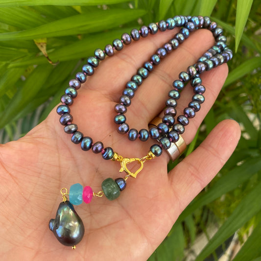 Black pearl necklace with chalcedony and chrysoprase held in hand showing removable gemstone pendant