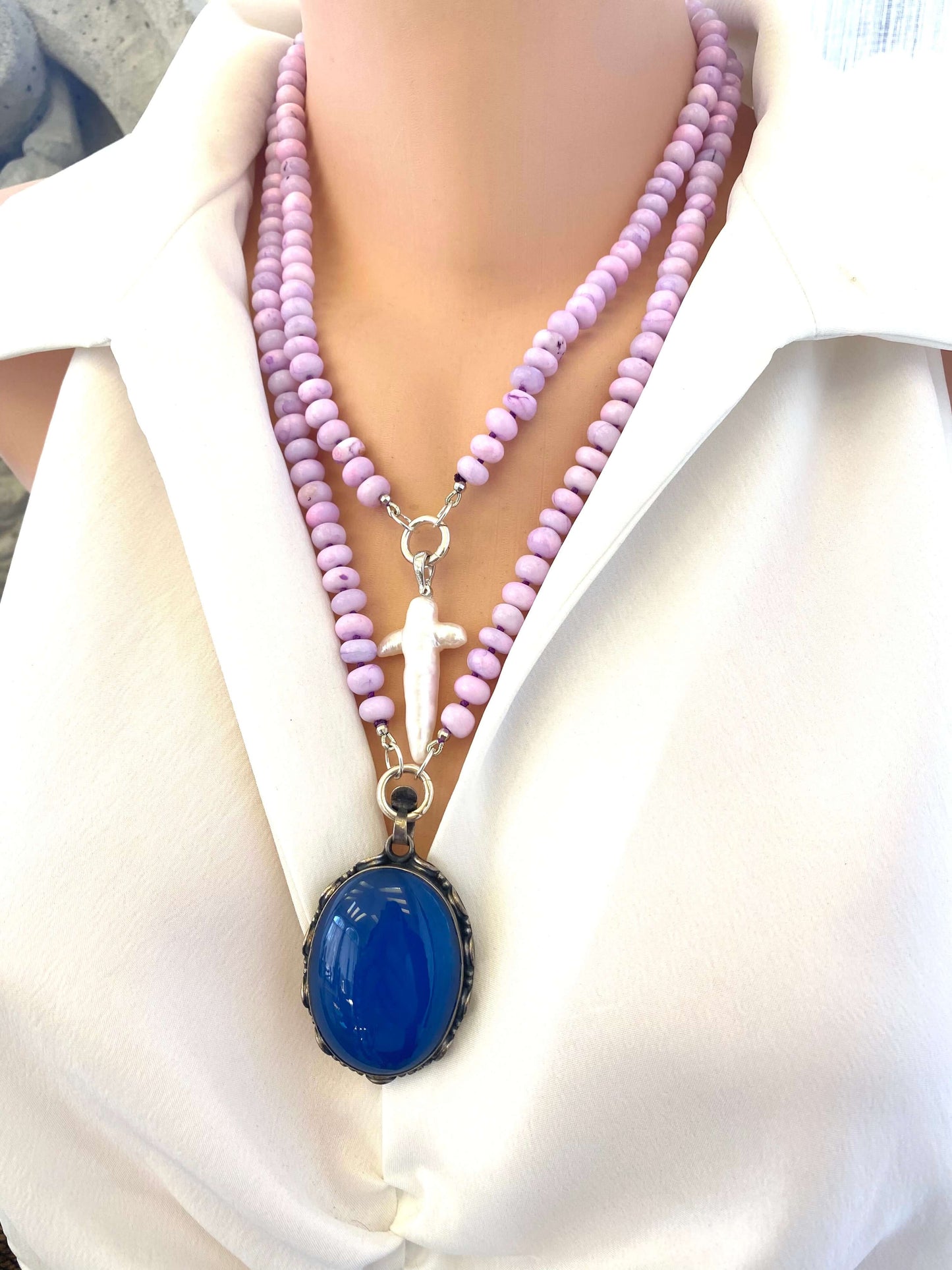 → Lavender opal necklace displayed with white pearl cross and blue agate pendants, handmade gemstone jewelry.