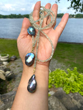 Load image into Gallery viewer, Green Prehnite and Black Baroque Pearls Lariat Necklace held outdoors by a hand, showcasing its elegance and craftsmanship.
