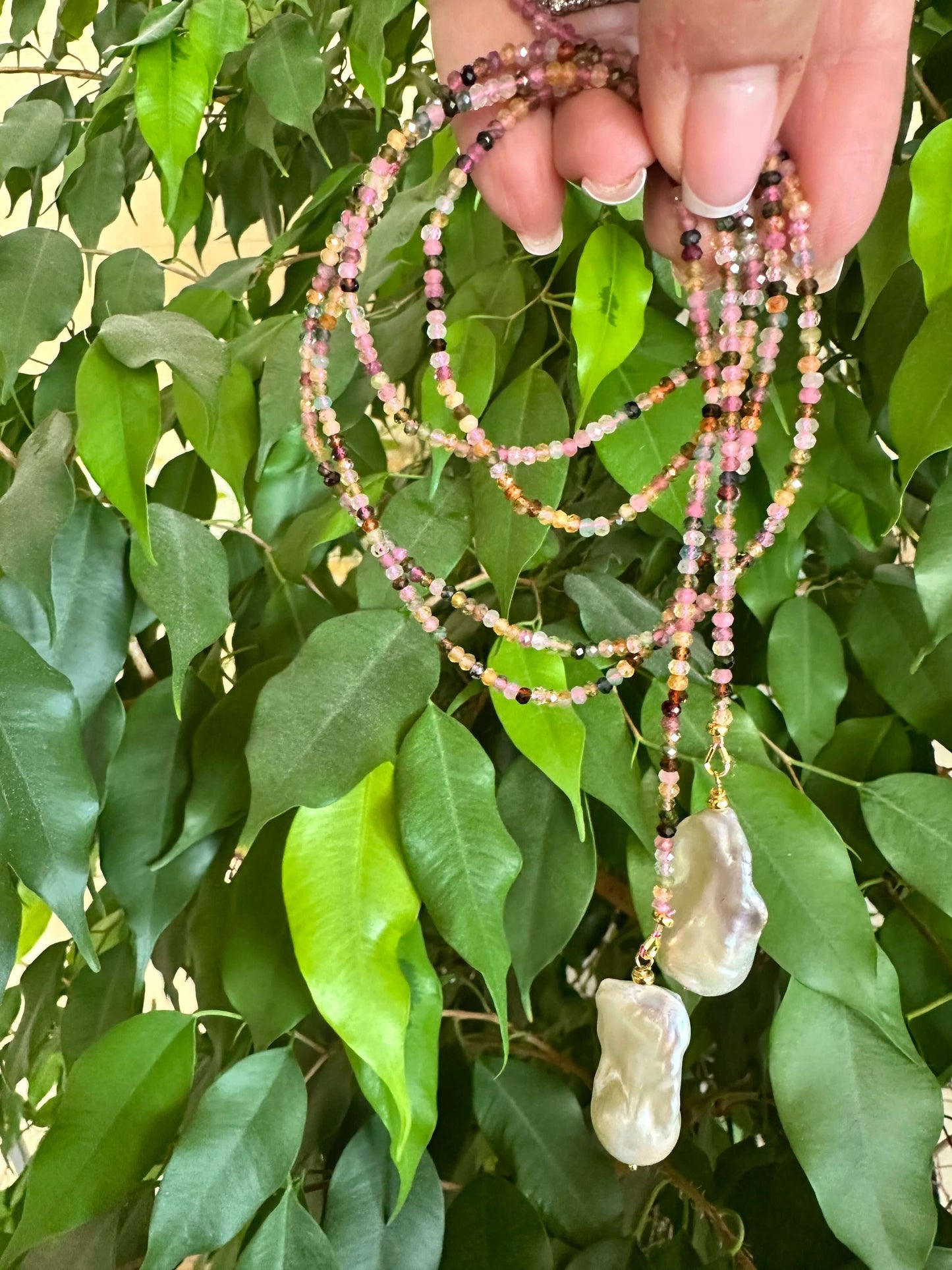 Multi Tourmaline Baroque Pearl Lariat Necklace held against green leaves — natural gemstone and pearl jewelry handcrafted by Loulia Pearl Jewelry