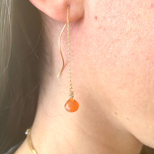 Carnelian threader earrings with vibrant orange briolettes, handmade in Canada, showcased on model's ear.
