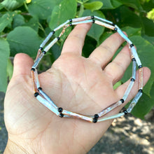 Load image into Gallery viewer, Pastel stick pearl necklace featuring stick pearls in pastel hues and black spinel accents, hand displayed against greenery.
