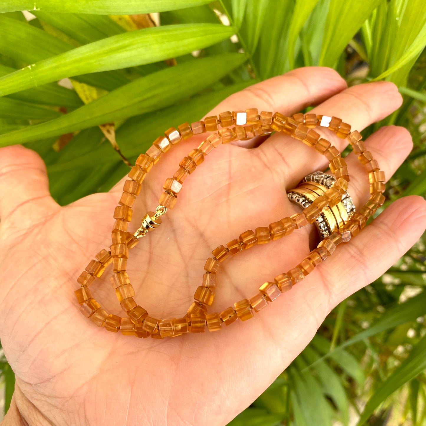 Hessonite garnet necklace displayed on a hand, showcasing warm golden-yellow cube stones with a magnetic clasp.