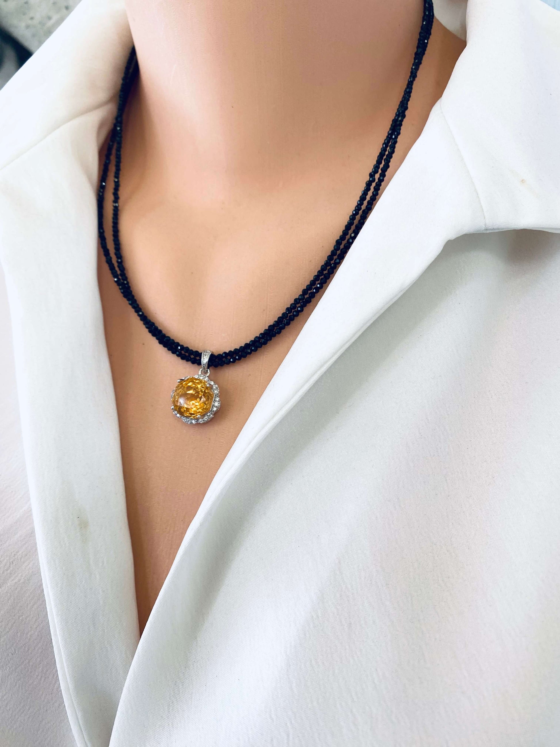 Side view of black spinel and citrine pendant necklace displayed on mannequin