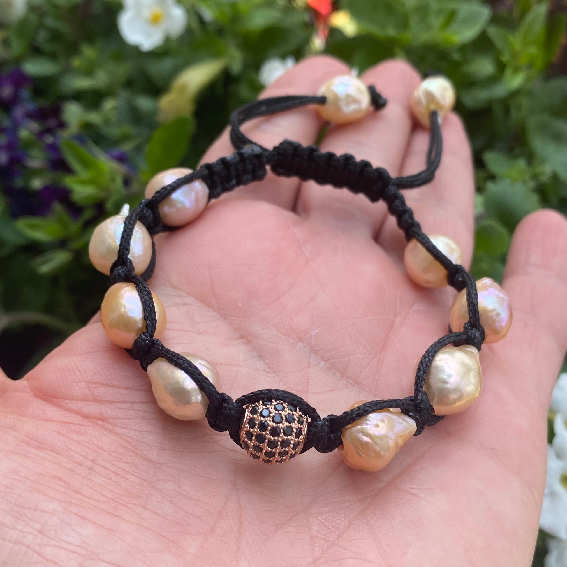 Baroque pearl bracelet with pastel pearls and black thread, showcasing unique baroque textures in a braided design.