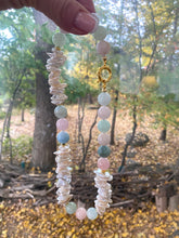 Charger l&#39;image dans la galerie, Aquamarine Morganite Necklace – held by hand against green foliage backdrop
