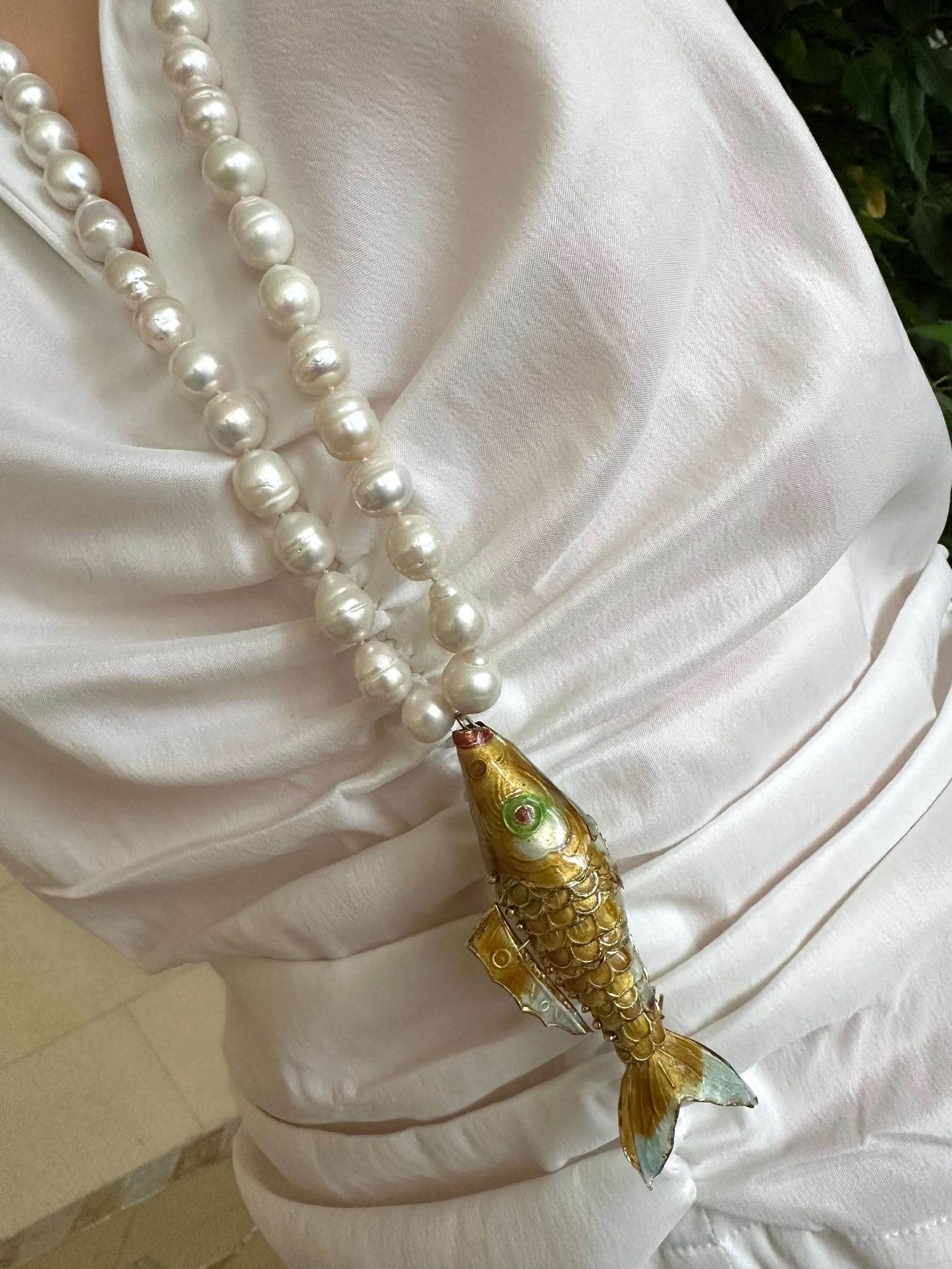 Baroque pearl necklace with fish pendant worn by a model, showcasing 9–11mm white baroque pearls and a gold-tone fish design.