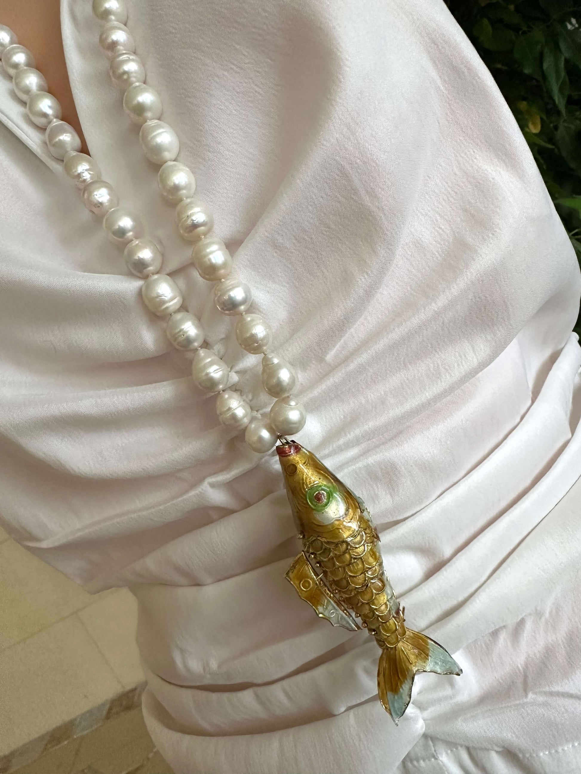 Baroque pearl necklace with fish pendant worn by a model, showcasing 9–11mm white baroque pearls and a gold-tone fish design.