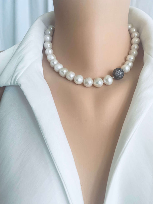 White Edison pearl necklace with gunmetal pavé magnetic clasp worn around the neck, featuring large luminous round pearls.