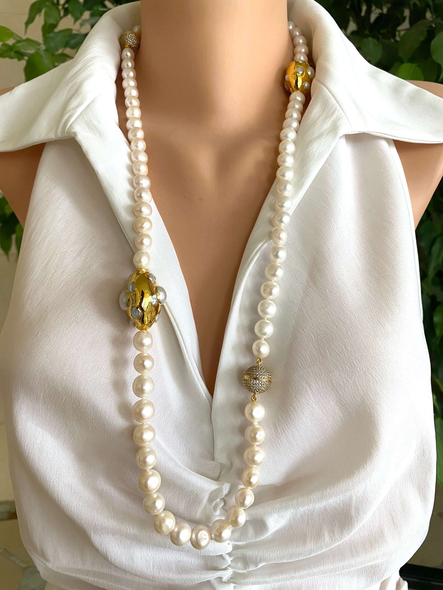 White potato pearl necklace with gold focal accent displayed on a mannequin in a white blouse.