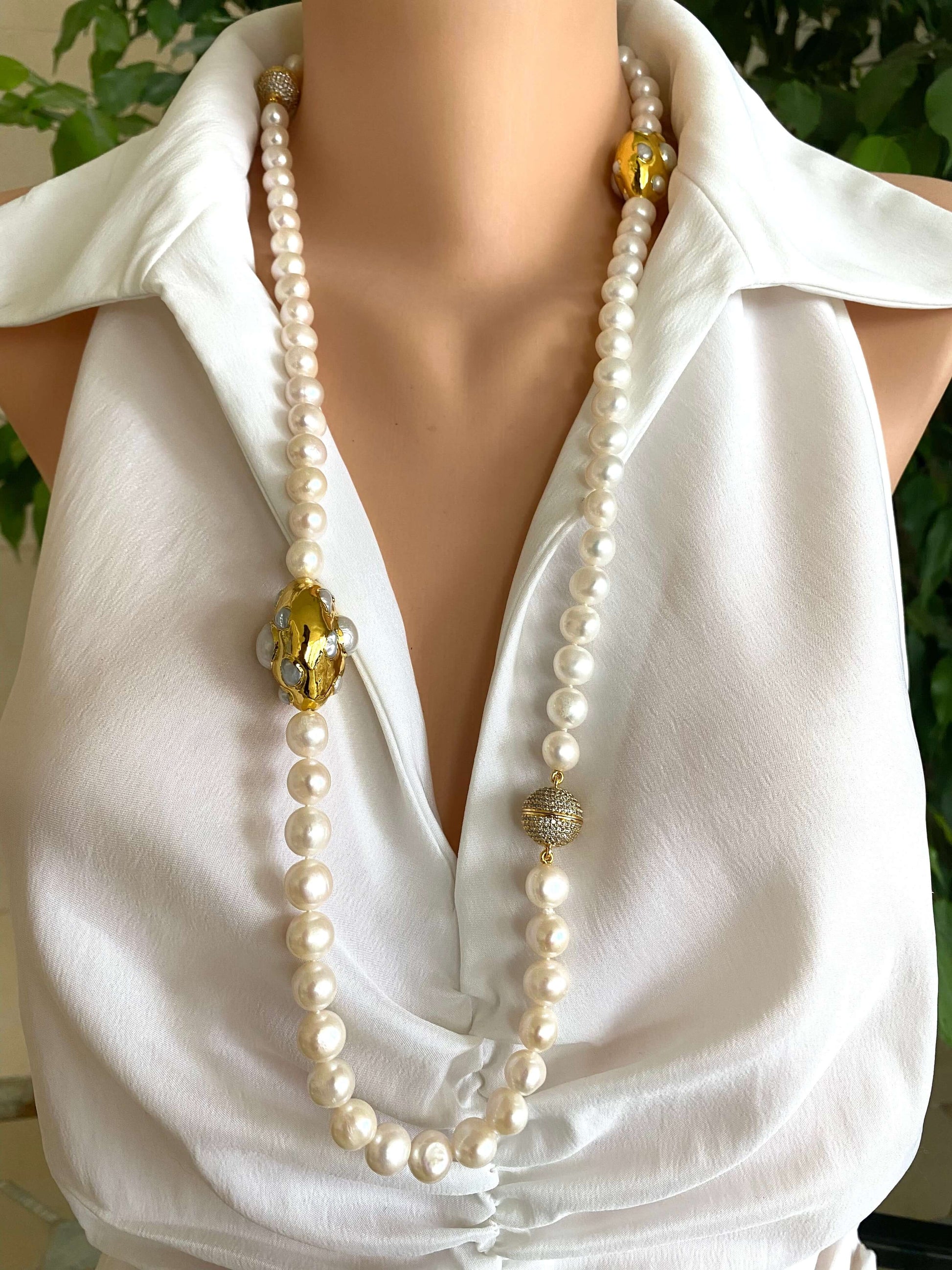 White potato pearl necklace with gold focal accent displayed on a mannequin in a white blouse.