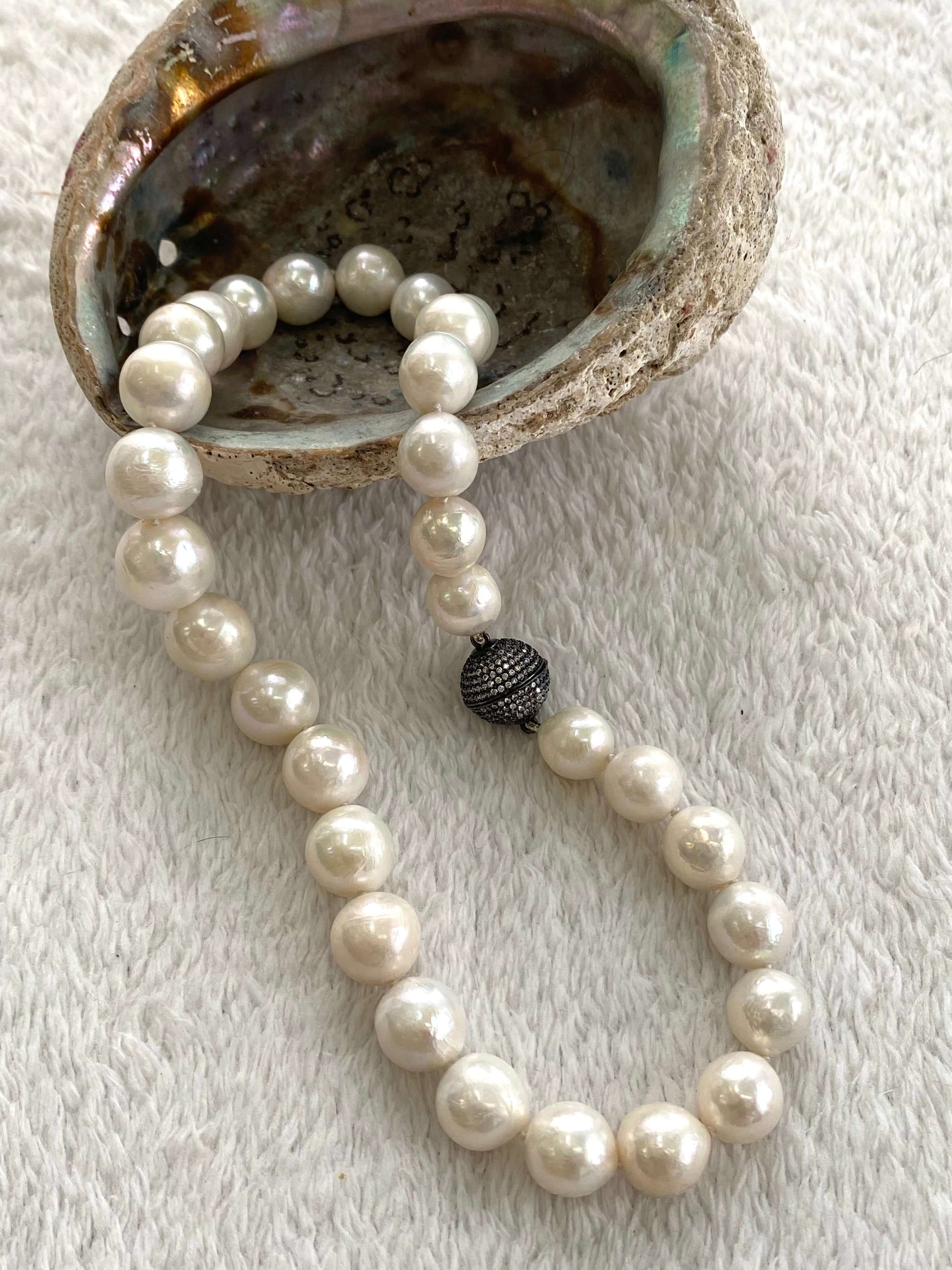 White Edison pearl necklace with large pearls and gunmetal pavé magnetic clasp displayed on a shell.