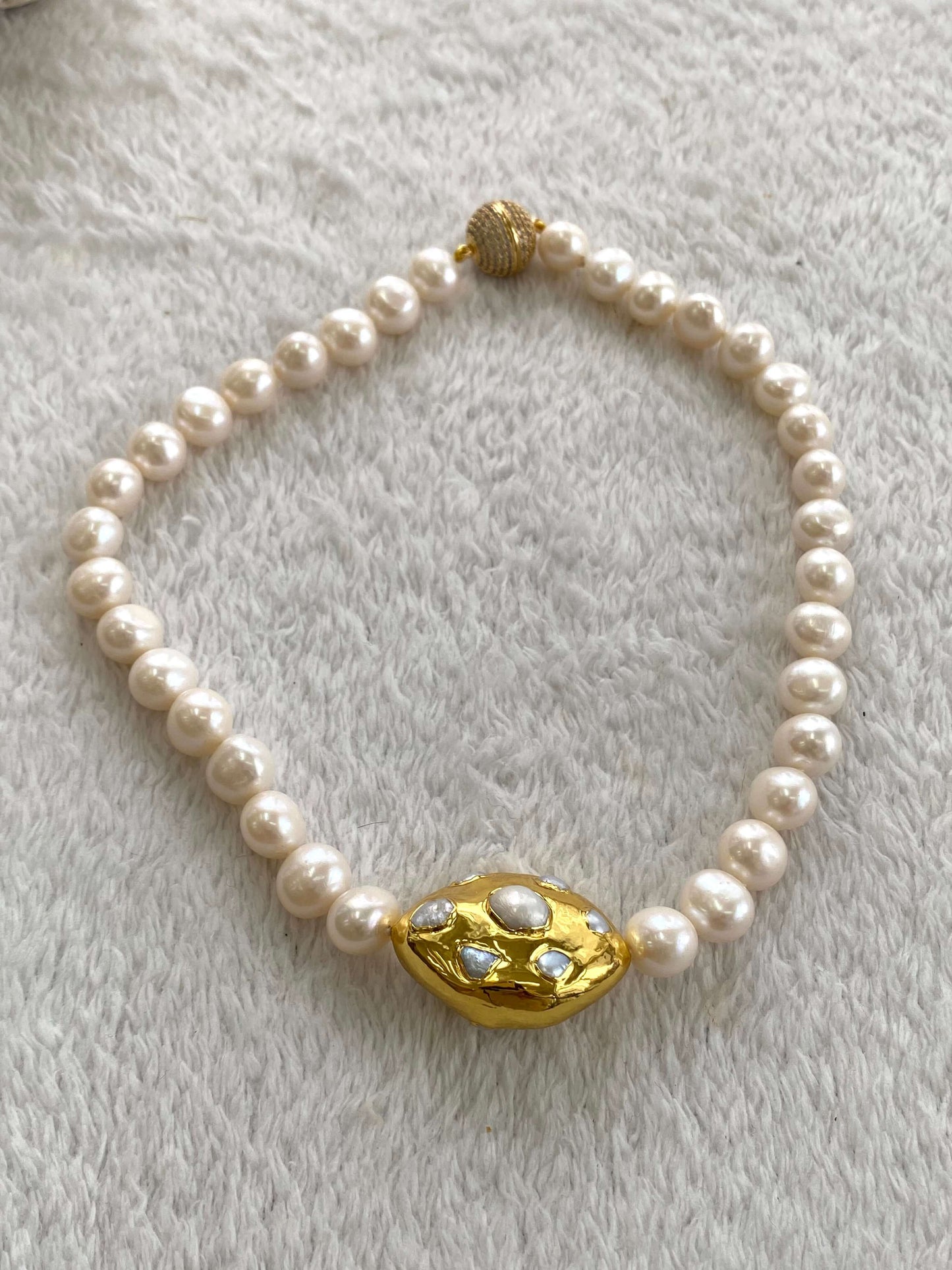 White potato pearl necklace with gold focal accent, featuring hand knotted white potato pearls and a shimmering gold centerpiece.