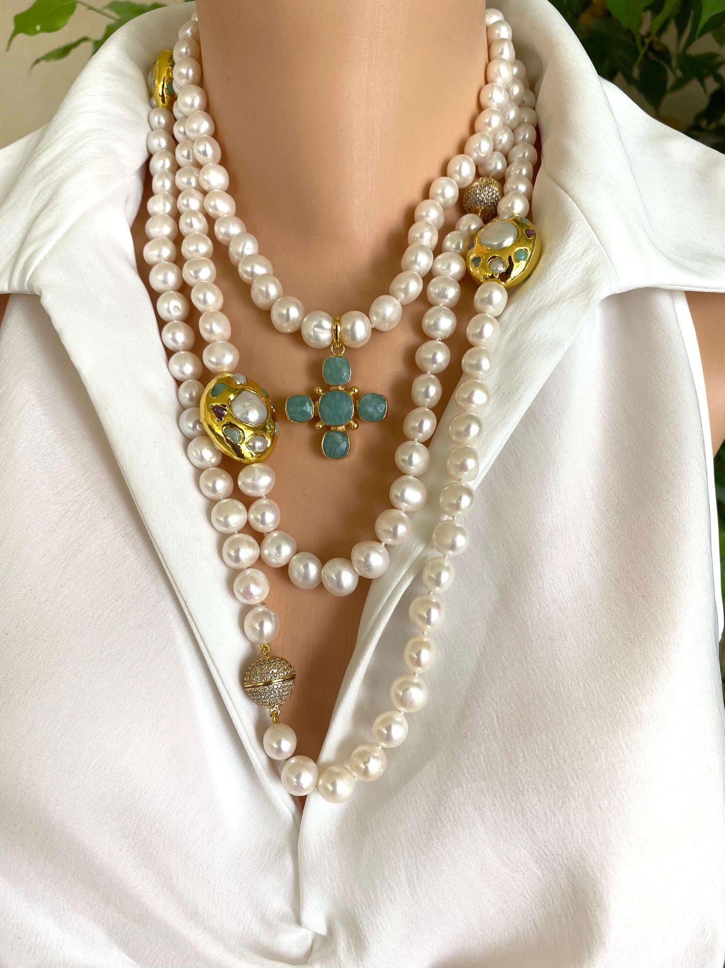 White pearl necklace with gold accent displayed on a model, featuring multiple strands and a decorative centerpiece.