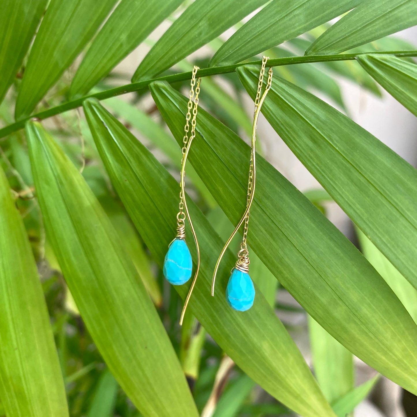 Turquoise threader earrings featuring Arizona briolettes displayed against green foliage.