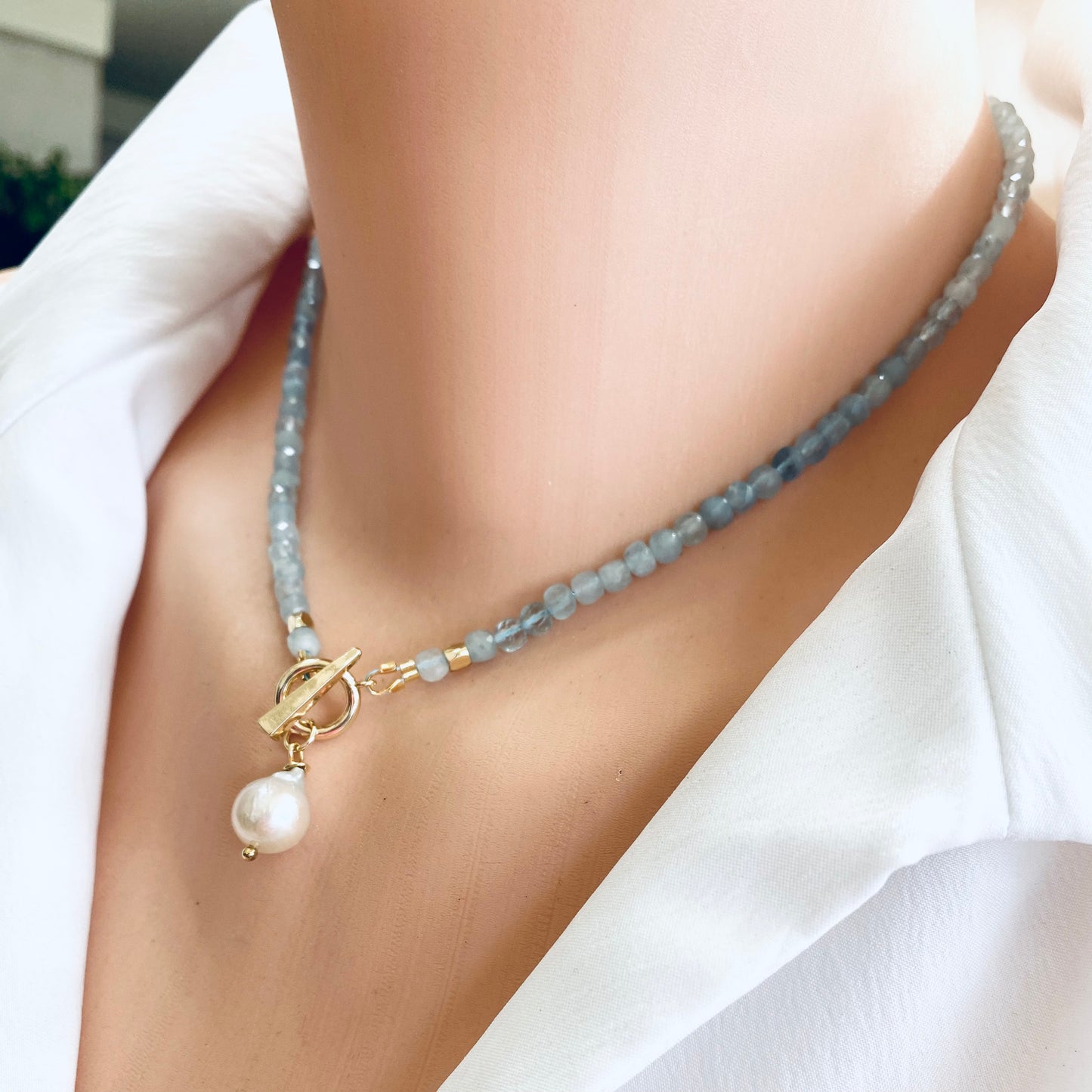 Aquamarine toggle necklace with baroque pearl pendant displayed on a mannequin, showcasing elegant craftsmanship and soothing colors.