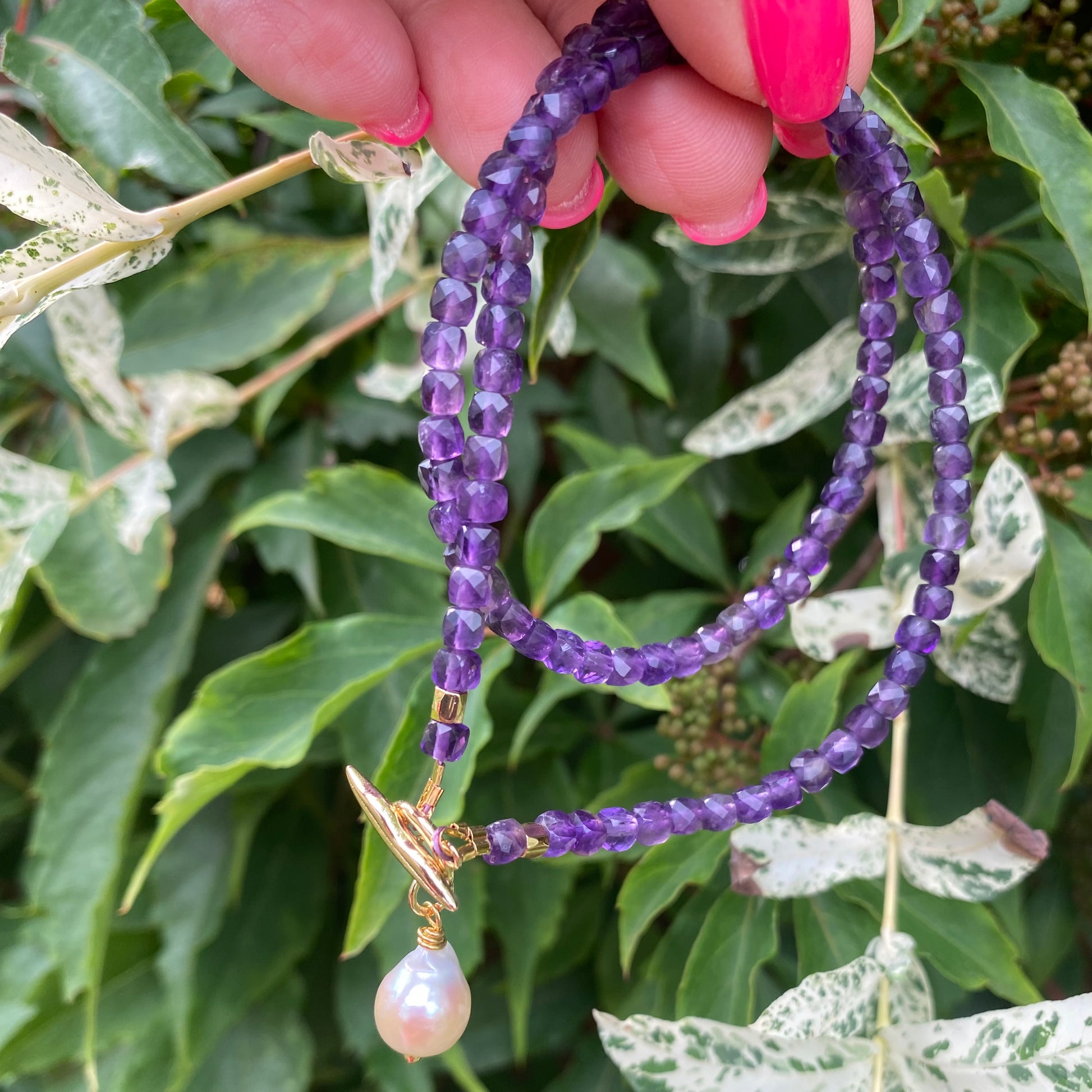 Amethyst toggle necklace with baroque pearl charm, showcasing faceted amethyst cube beads in rich purple hues.