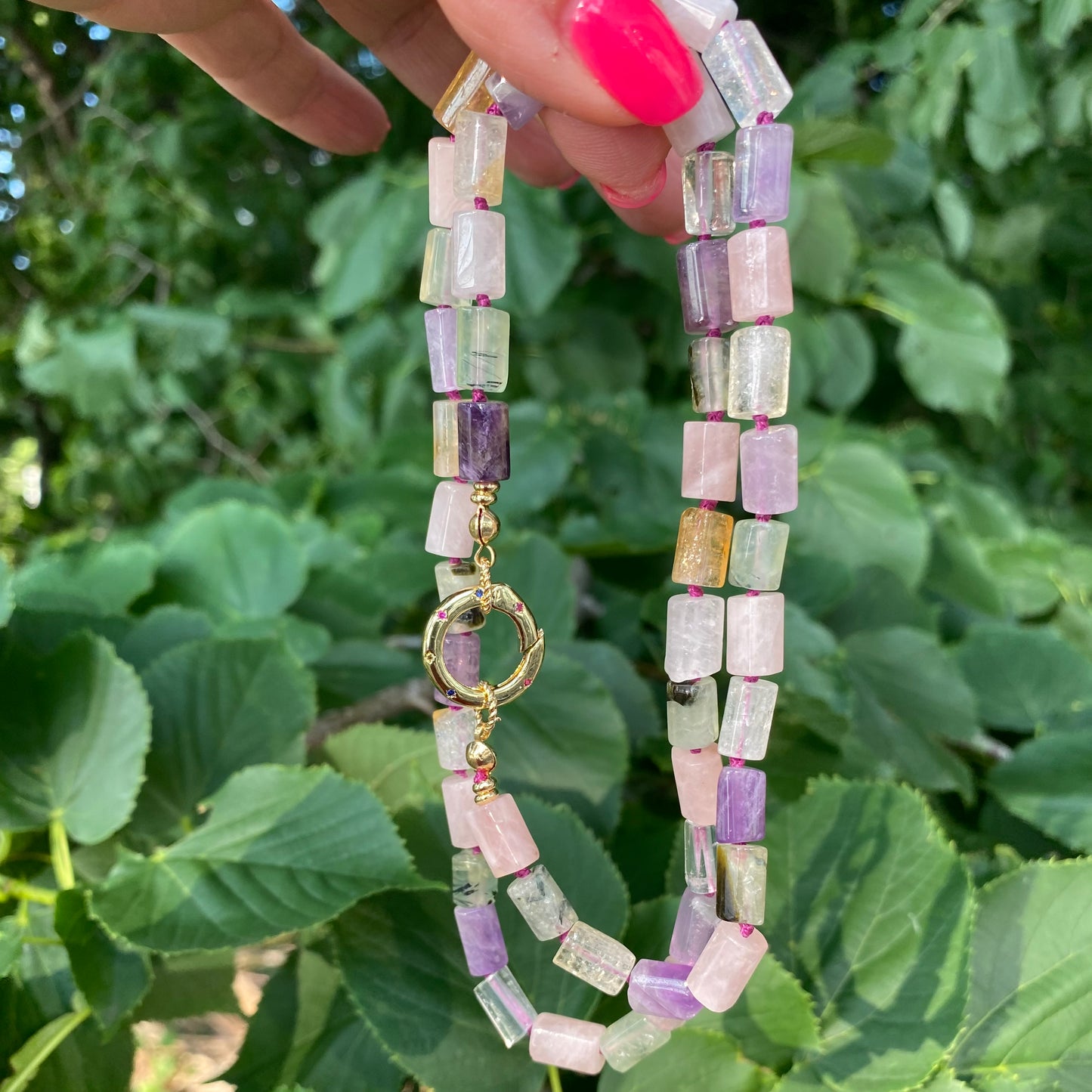 Mixed gemstone necklace with rose quartz, citrine, prehnite, and amethyst tube beads displayed outdoors, handmade jewelry from Canada