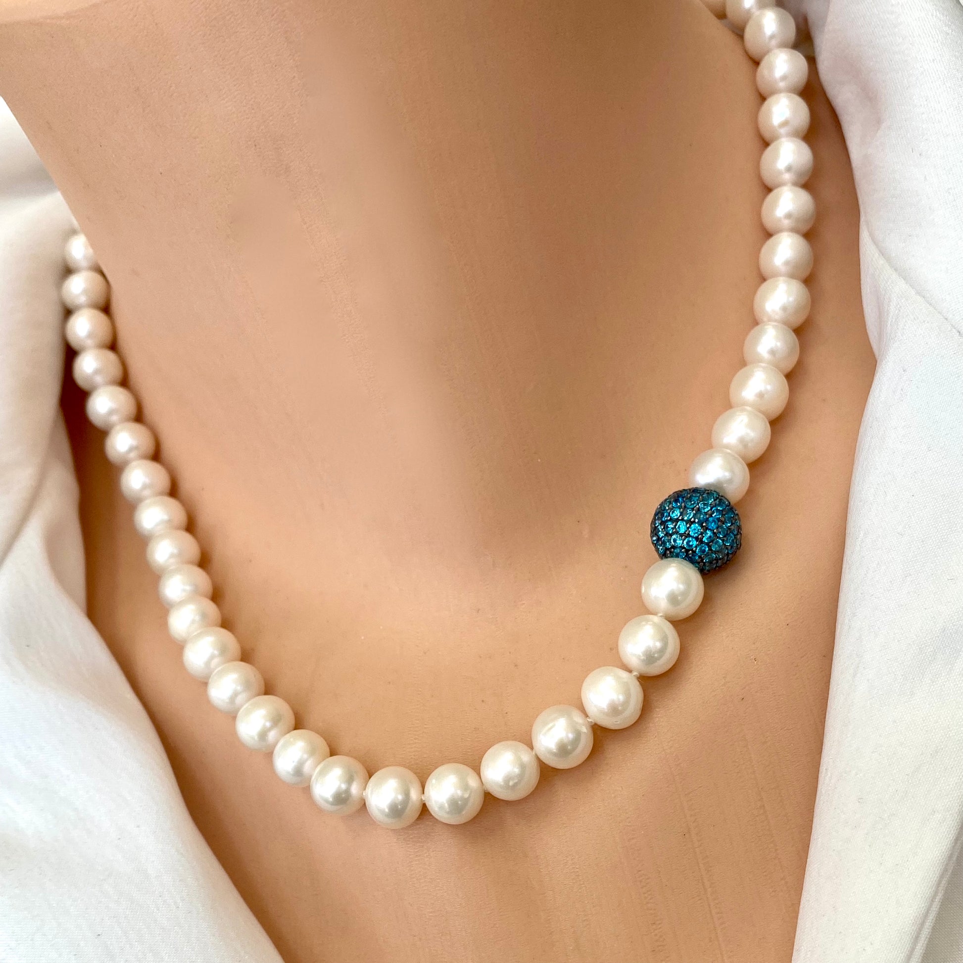 Pearl necklace with turquoise CZ bead on display, handcrafted in Canada, showcasing classic elegance and modern color.