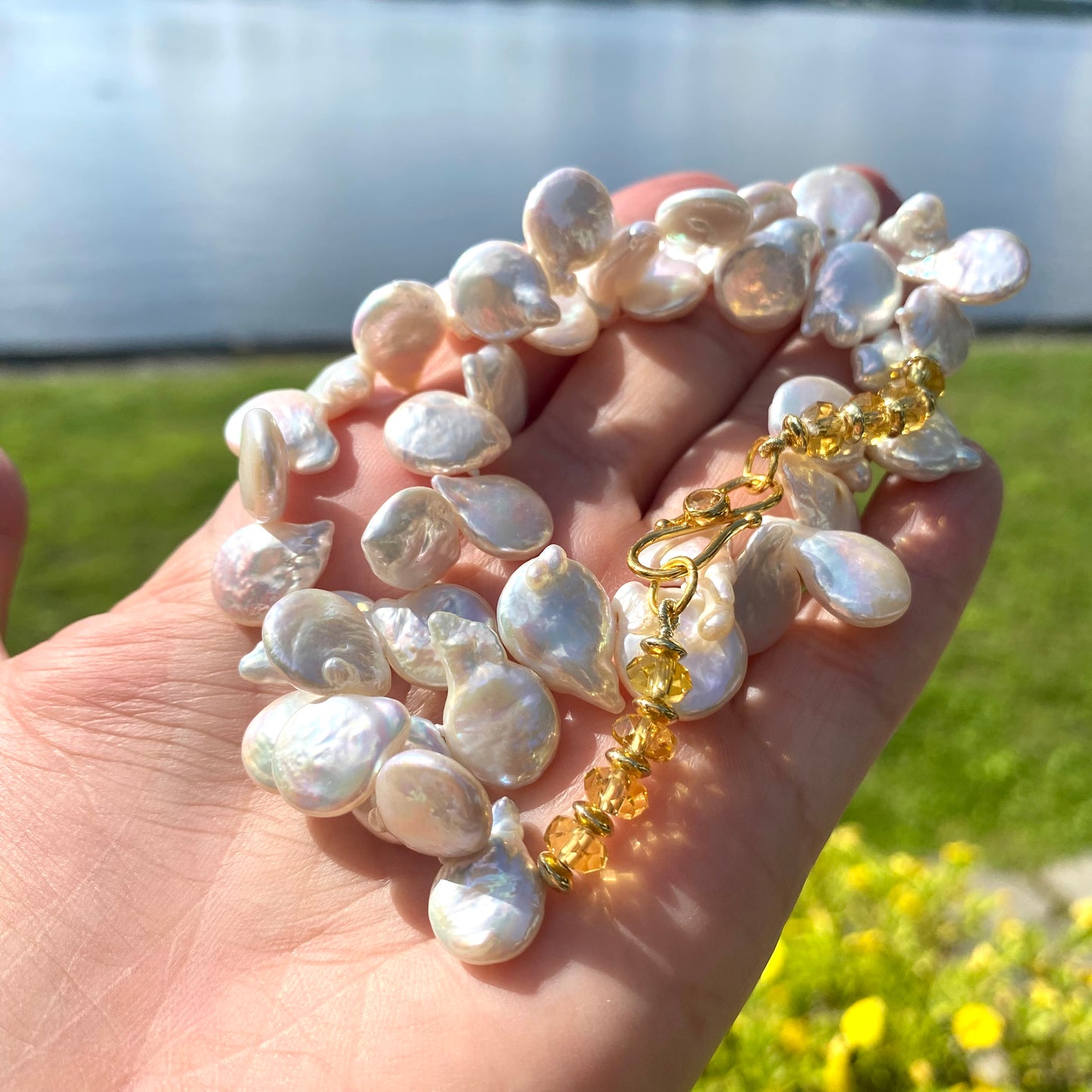 Keshi pearl necklace showcasing AAA-quality freshwater pearls with garnet or citrine accents in a natural outdoor setting.