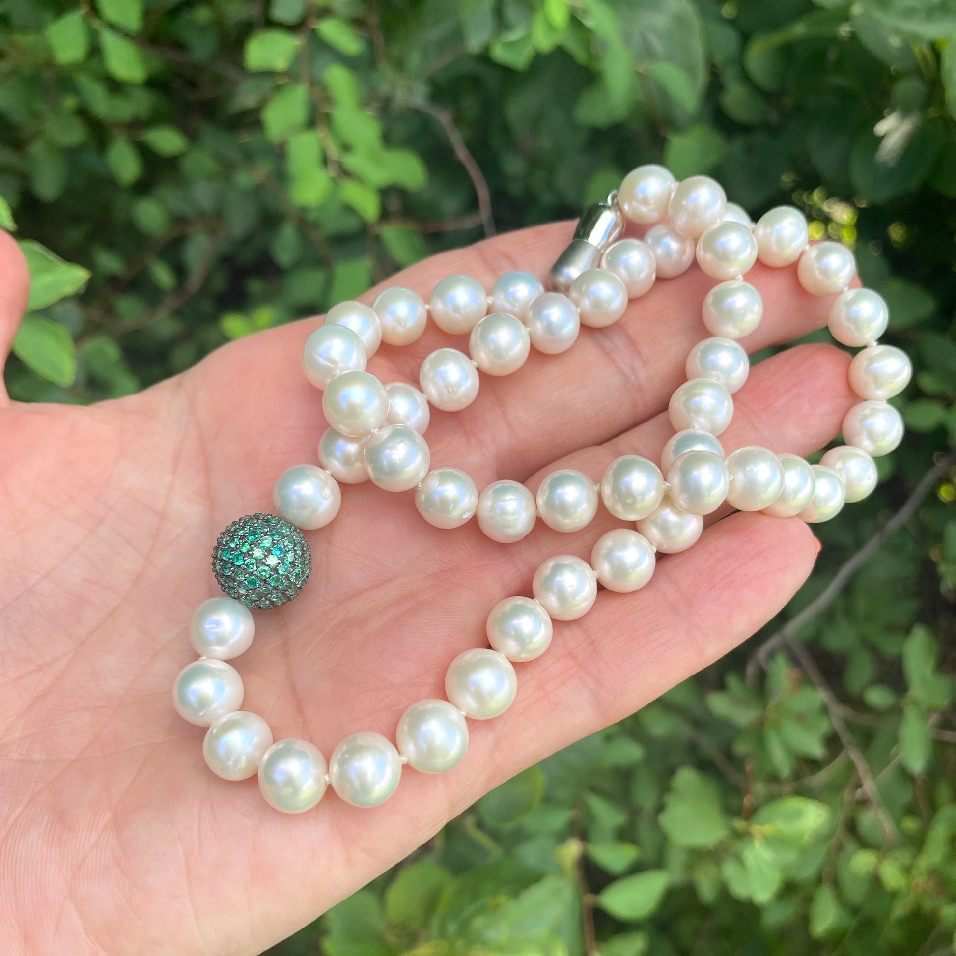 Handmade pearl necklace with a green CZ bead, featuring lustrous freshwater pearls on white thread.