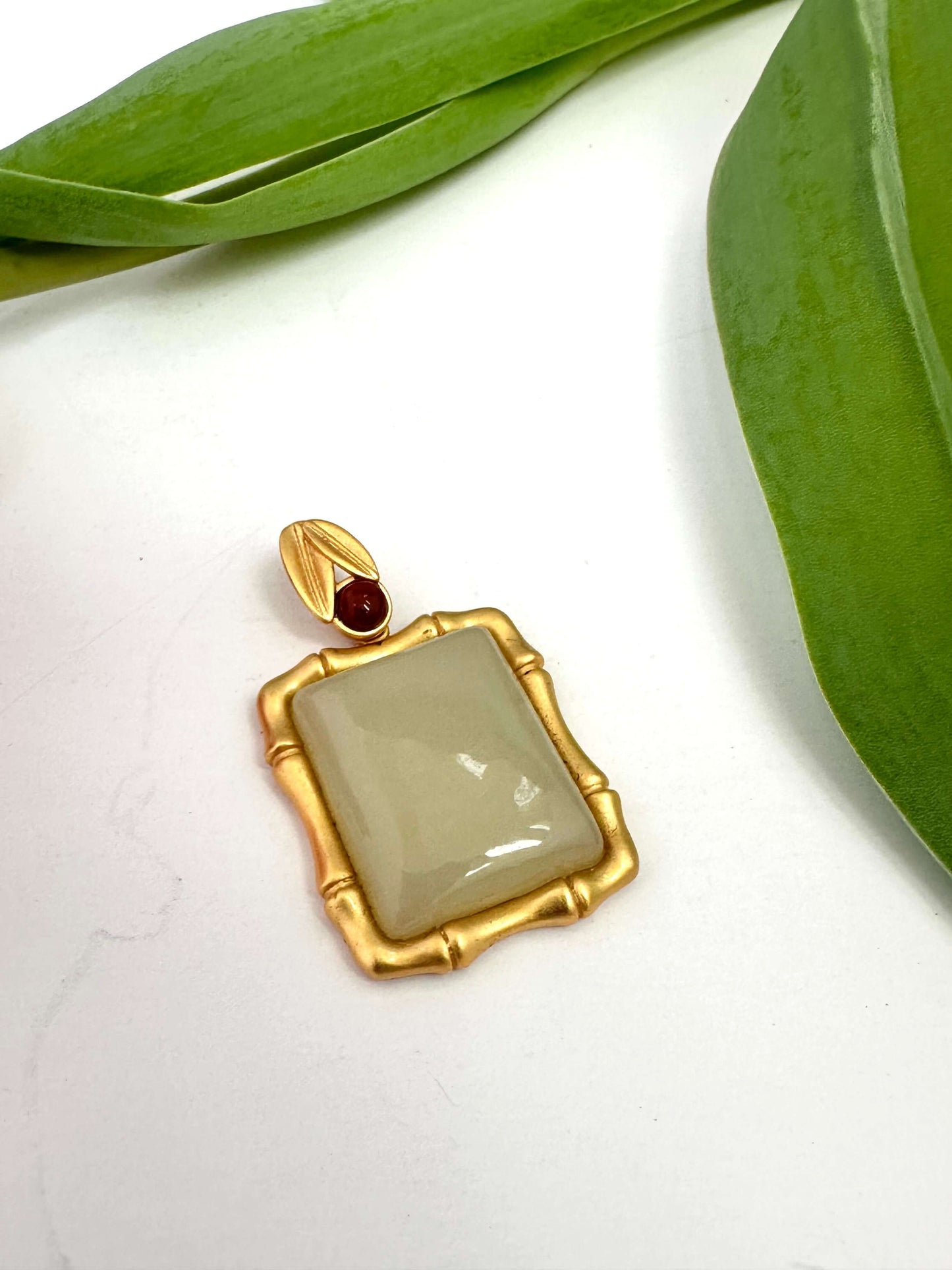 Bamboo style jade pendant with red agate in sculptural gold vermeil setting and unique jade tone variations.