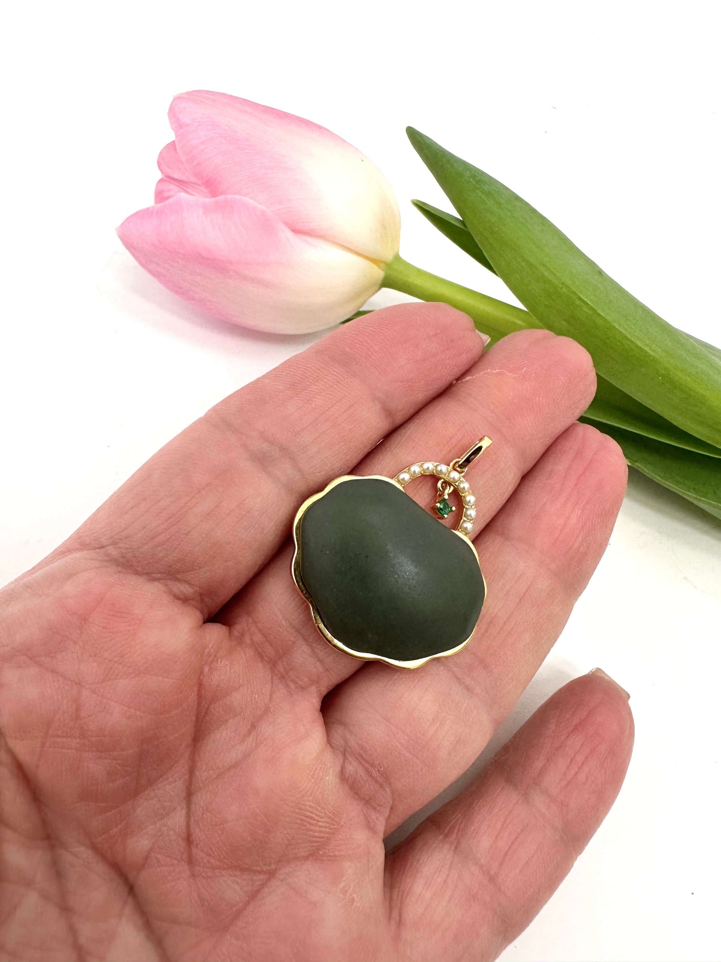 Hotan jade purse pendant with pearl detail held in hand, showcasing natural nephrite jade and gold vermeil details.