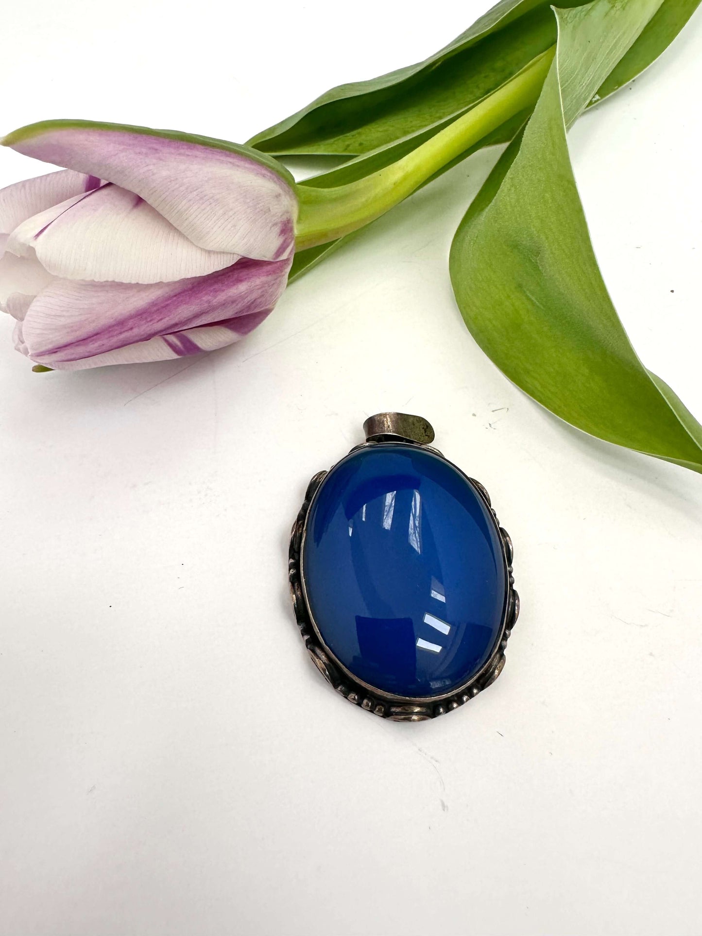 Vintage blue agate pendant in oxidized sterling silver with a purple tulip in the background.