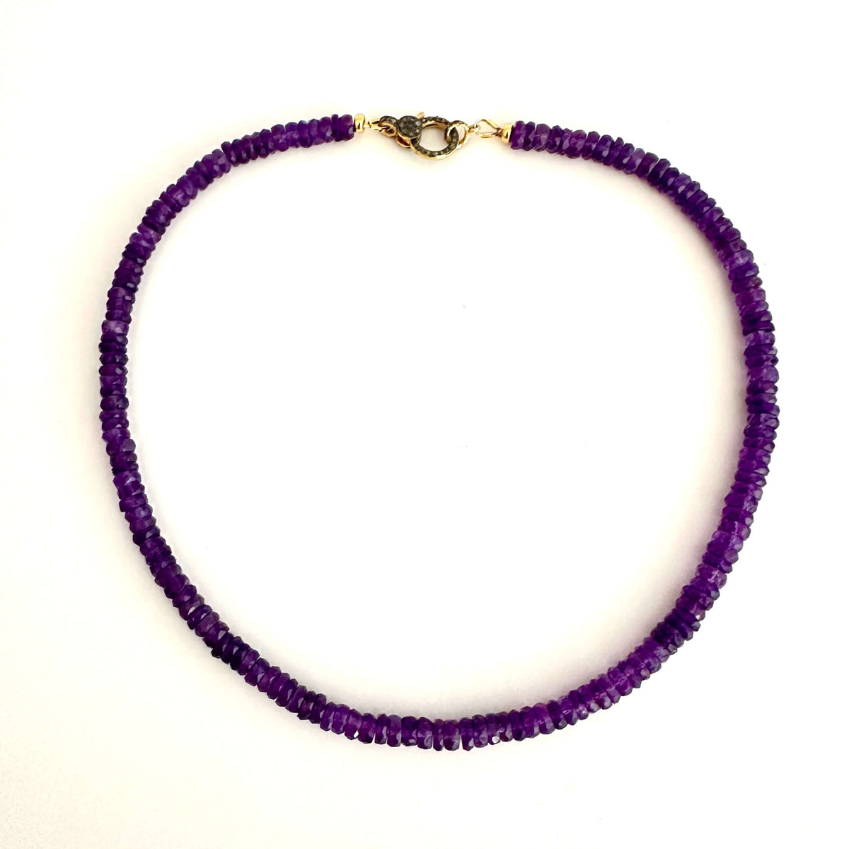 A beaded necklace made of small, faceted purple beads, featuring a gold-toned lobster clasp at the top, displayed on a clean white background.