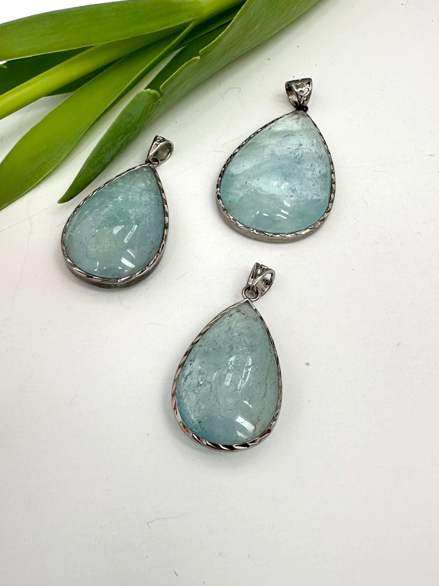 Aquamarine teardrop pendant in oxidized sterling silver showcasing pear-shaped stones and artisan finish.