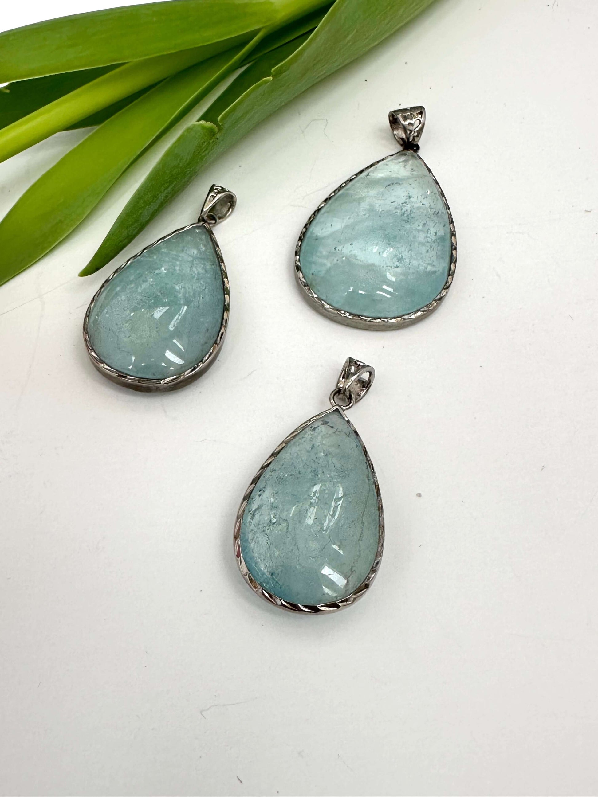 Aquamarine teardrop pendant in oxidized sterling silver showcasing pear-shaped stones and artisan finish.