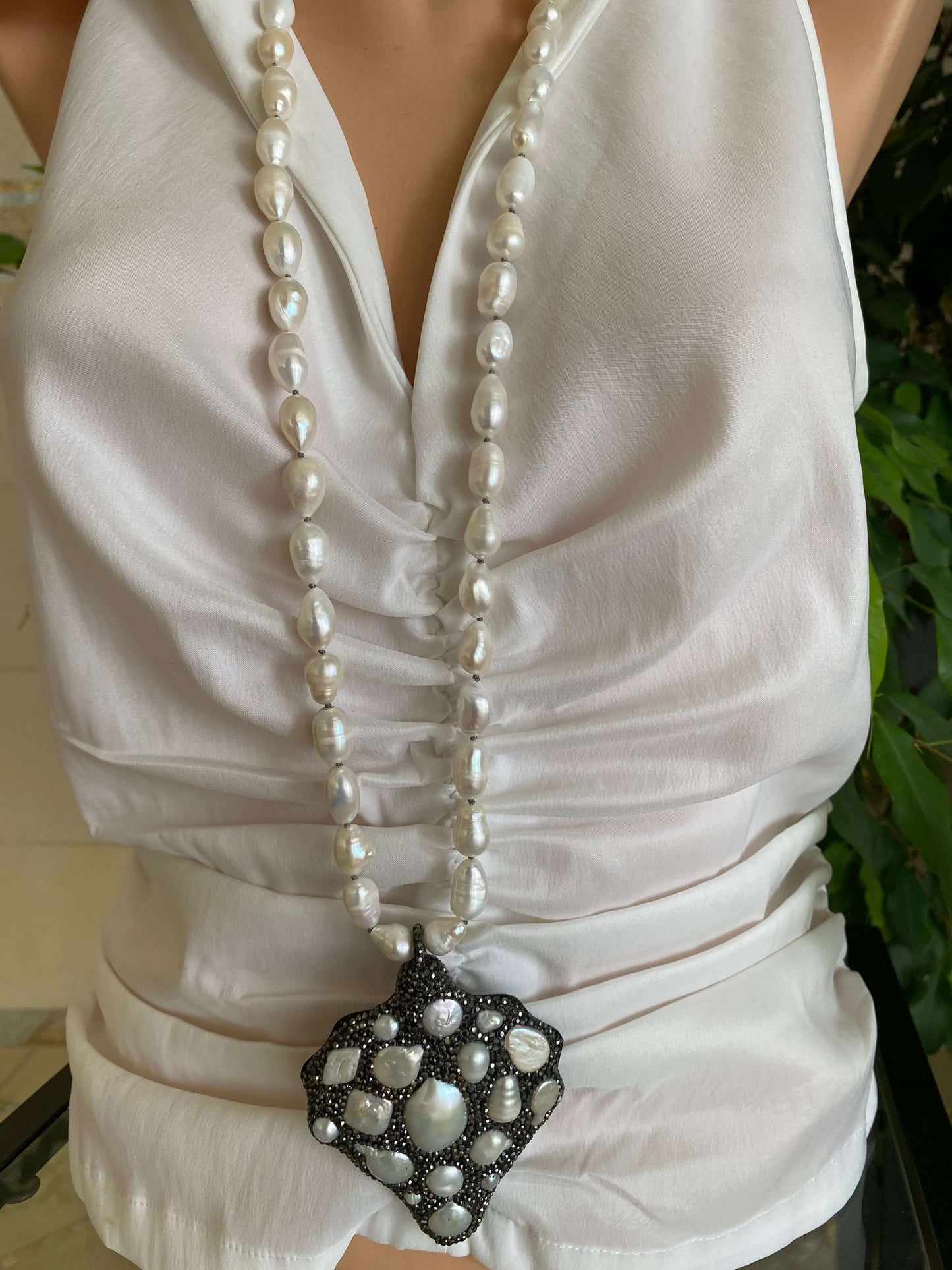 Long white pearl nugget necklace with pavé pendant styled on a model, showcasing luminous freshwater pearls.