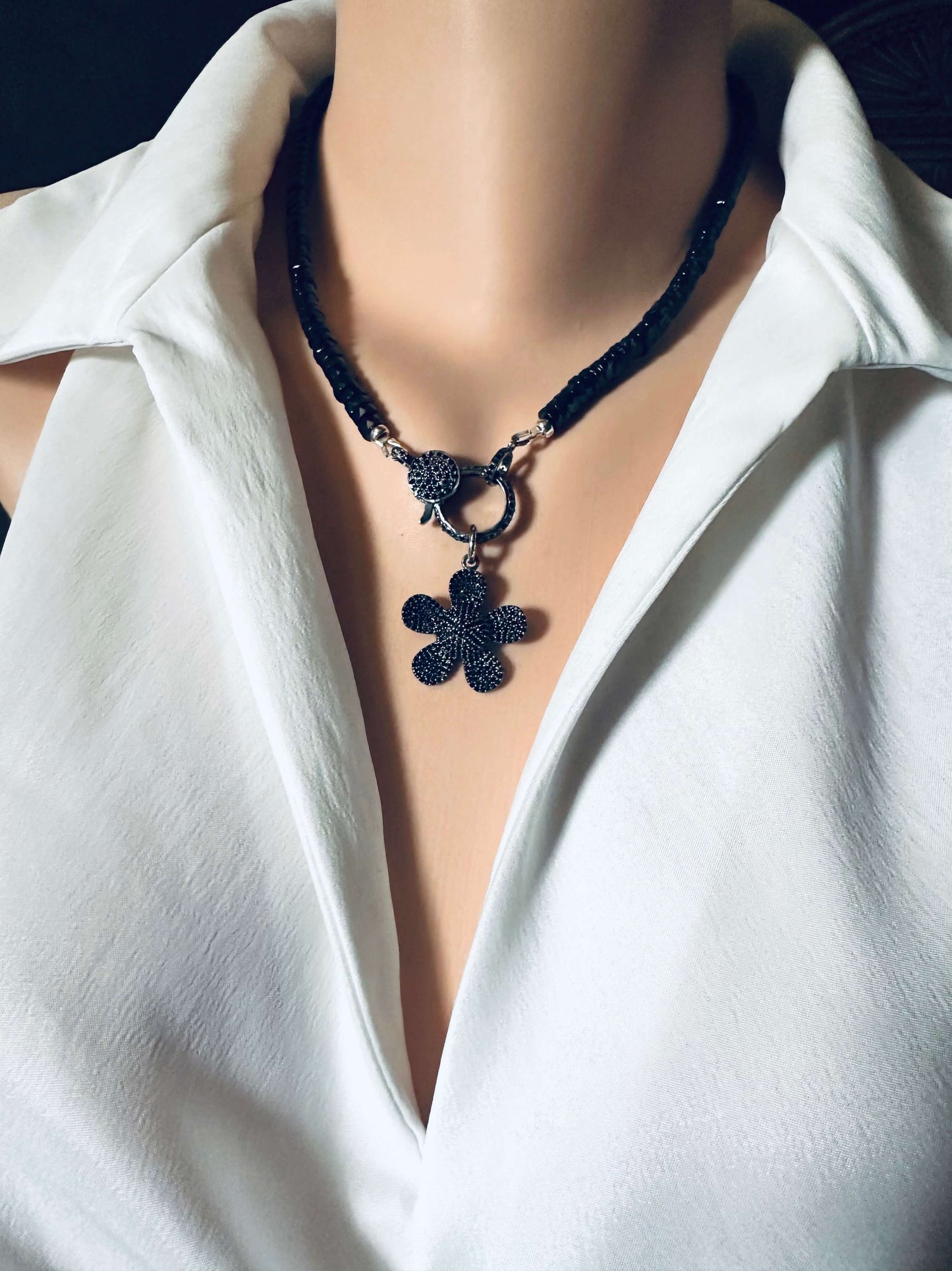 Black spinel daisy pendant necklace in oxidized silver displayed on a mannequin wearing a white blouse.