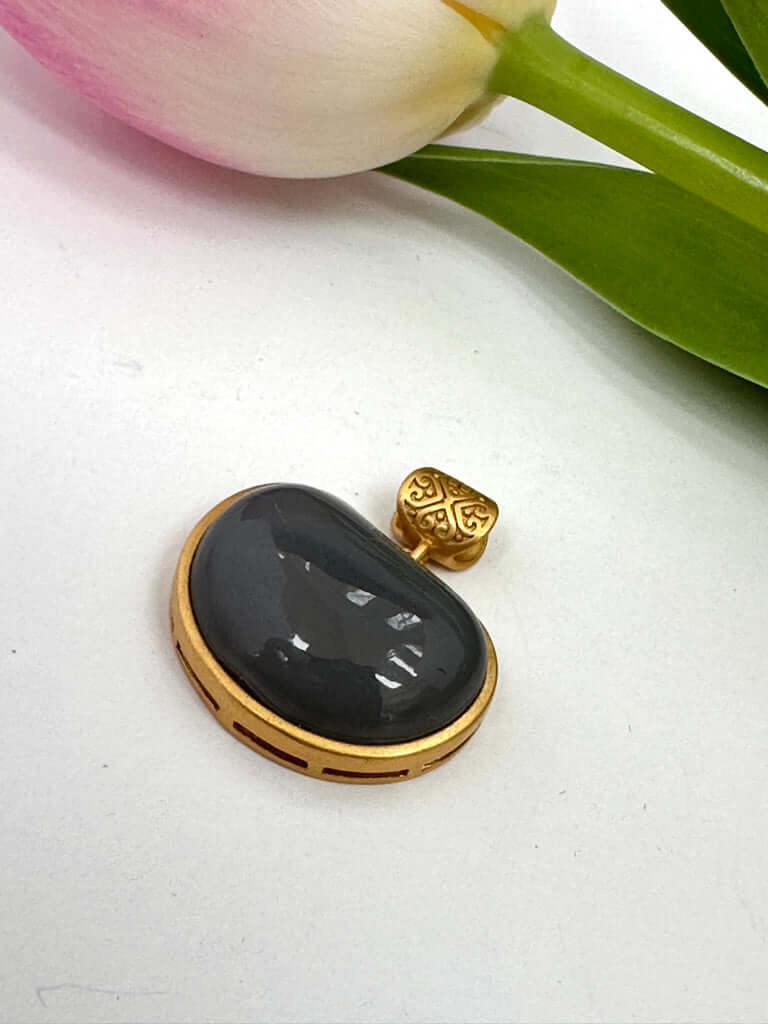 Hotan jade charm pendant in gold bezel showcasing smooth nephrite jade in teardrop shape.