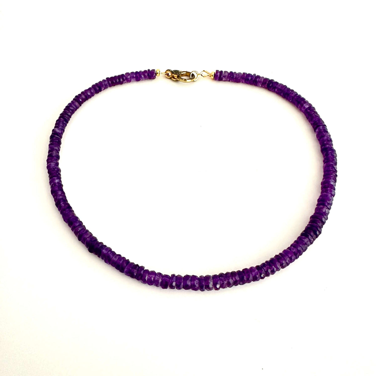 A beaded necklace made of small, faceted purple beads with a gold lobster clasp, displayed on a clean white background.
