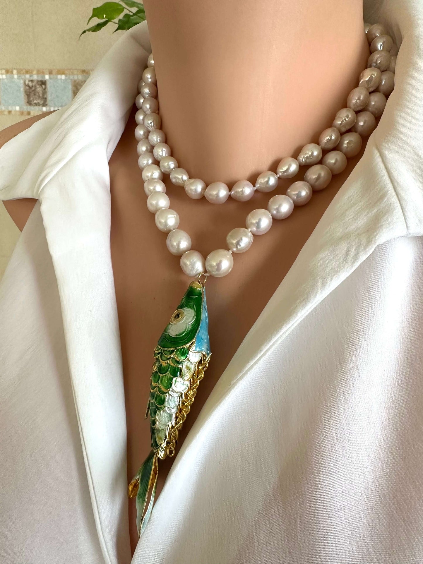 Cloisonné fish pearl necklace with hand knotted baroque pearls displayed on a mannequin wearing a white shirt.