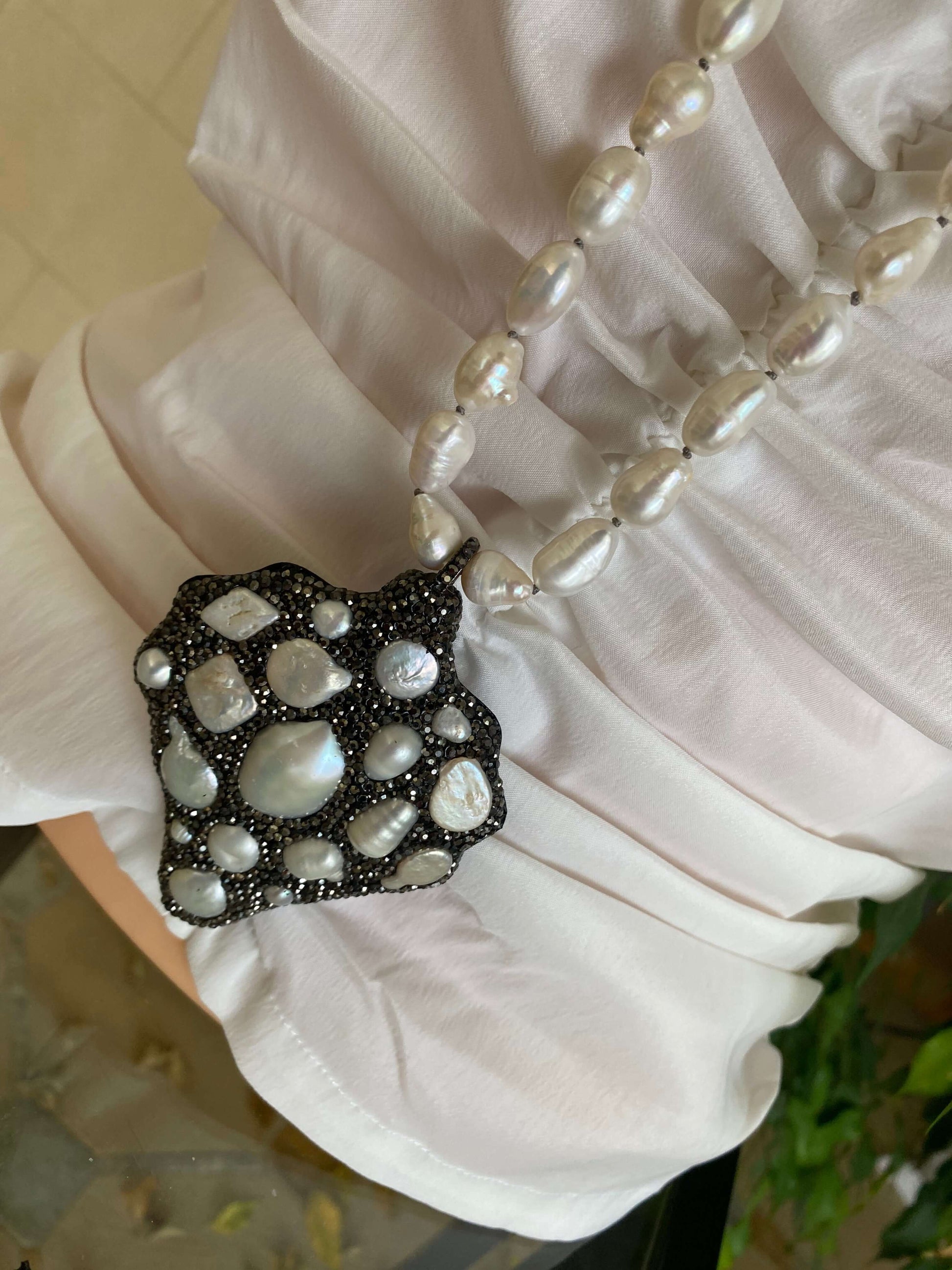 Long white pearl nugget necklace with pavé pendant displayed elegantly on a person, showcasing its unique design.