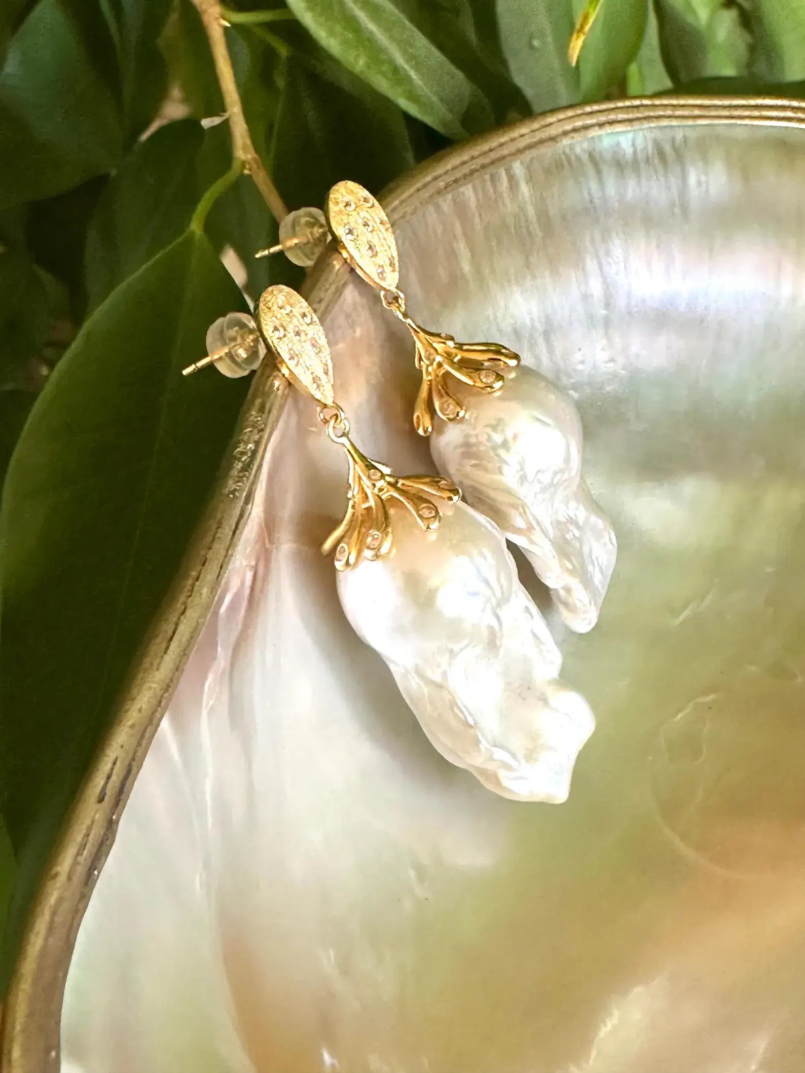 Detailed view of Baroque Pearl Gold Vermeil Earrings surrounded by pearls and green leaves — timeless handcrafted jewelry by Loulia Pearl Jewelry