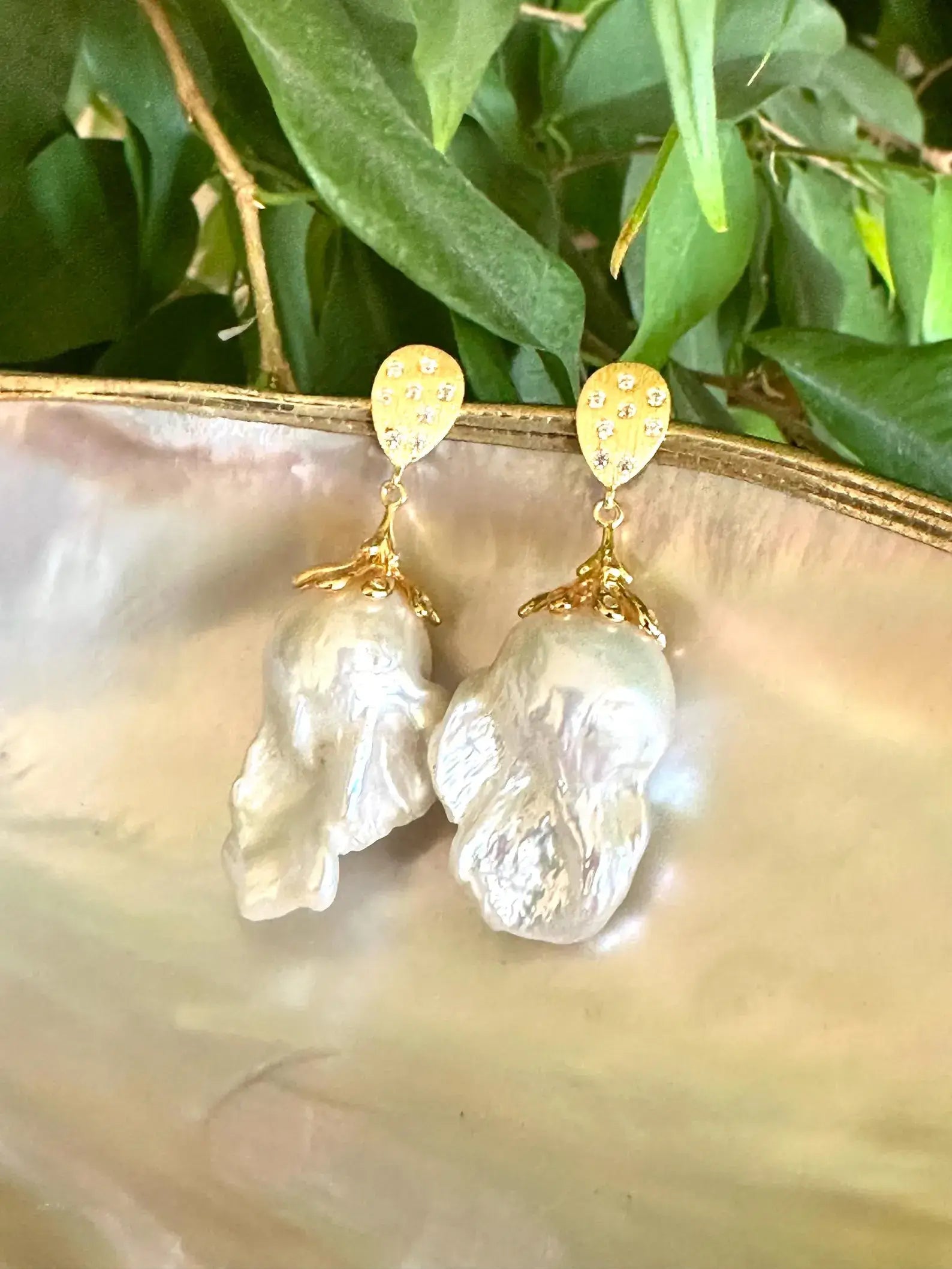 Handcrafted Baroque Pearl Gold Vermeil Earrings on white and green leaf backdrop — elegant pearl drop jewelry by Loulia Pearl Jewelry