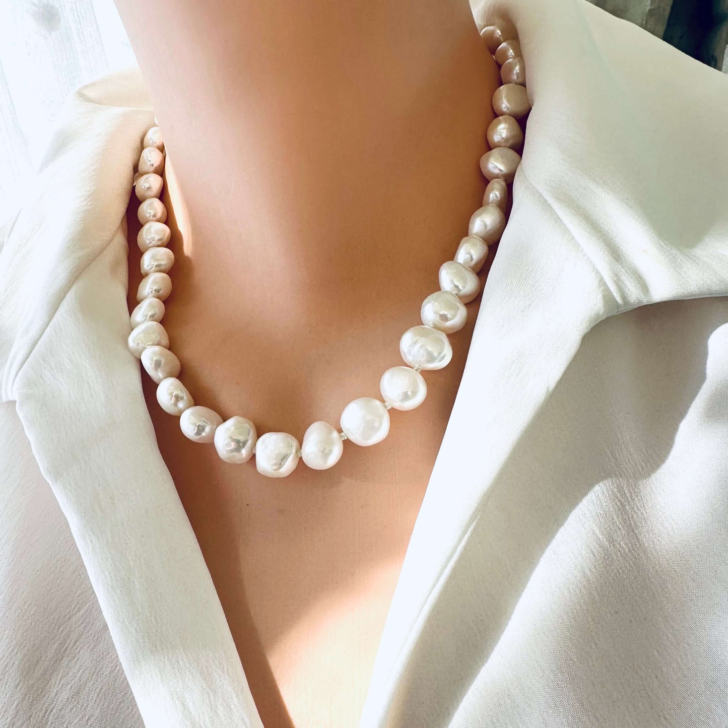 Small baroque pearl classic necklace showcasing lustrous freshwater pearls on a model's neckline.