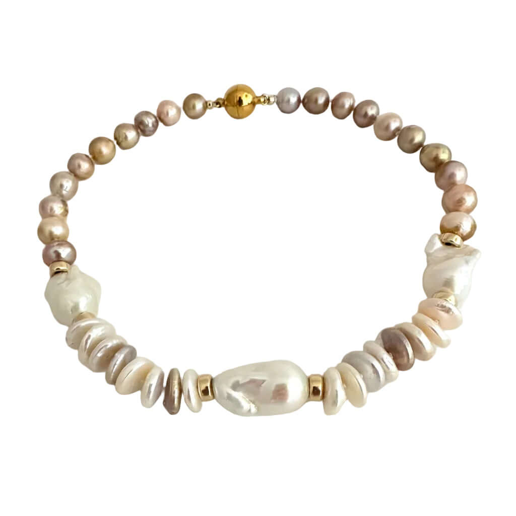 A beaded necklace featuring a mix of iridescent baroque pearls in beige, brown, and white, accented with small gold spacer beads and a gold clasp, displayed on a neutral light gray background.