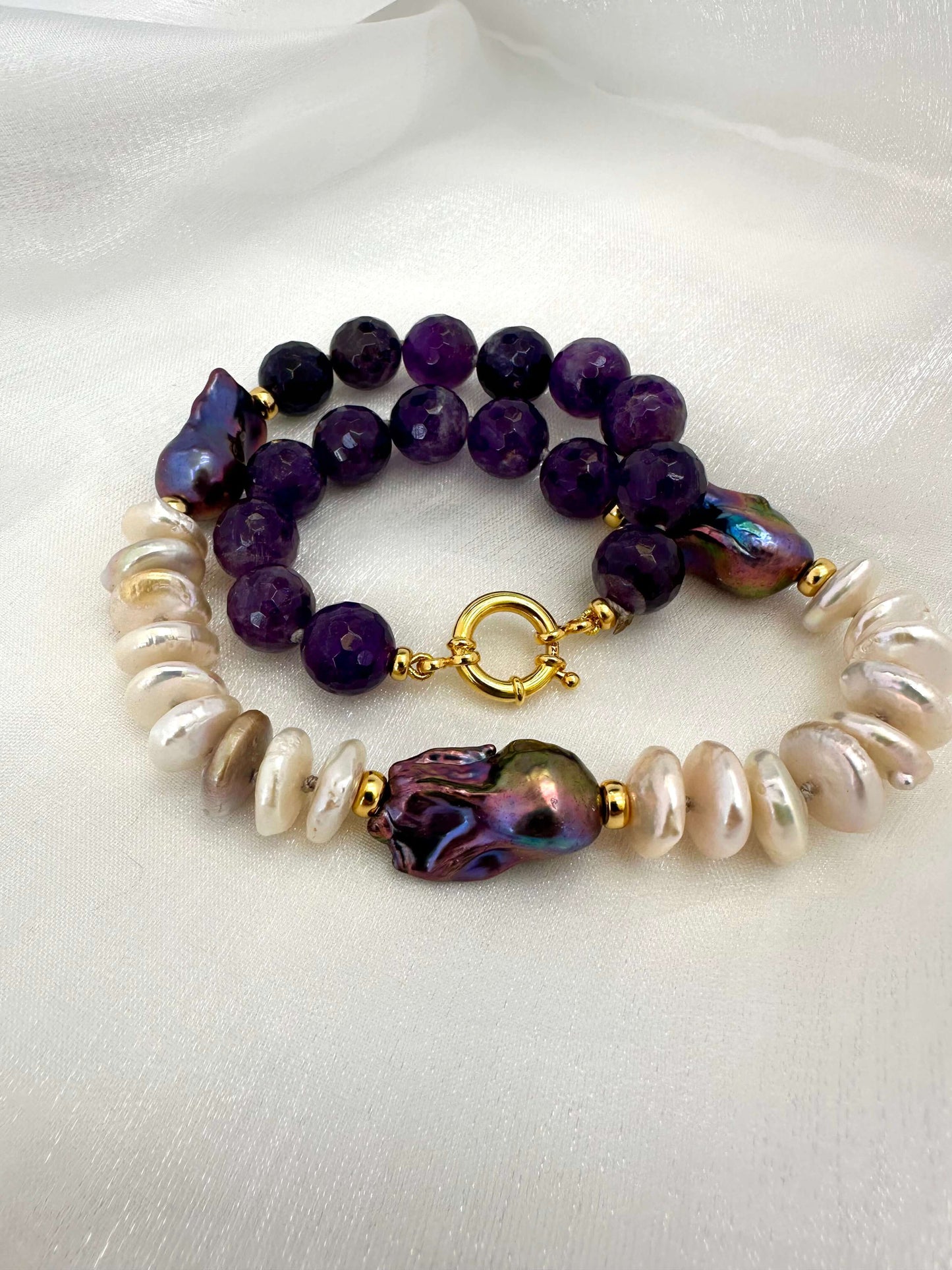 Close up of baroque pearl necklace with purple amethyst gemstones and marine clasp