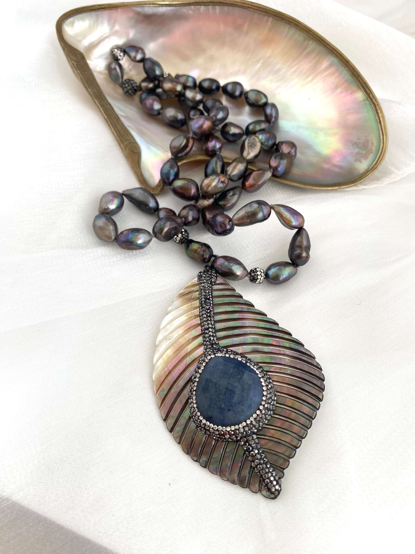 Long peacock black pearl necklace with abalone agate pendant displayed elegantly.