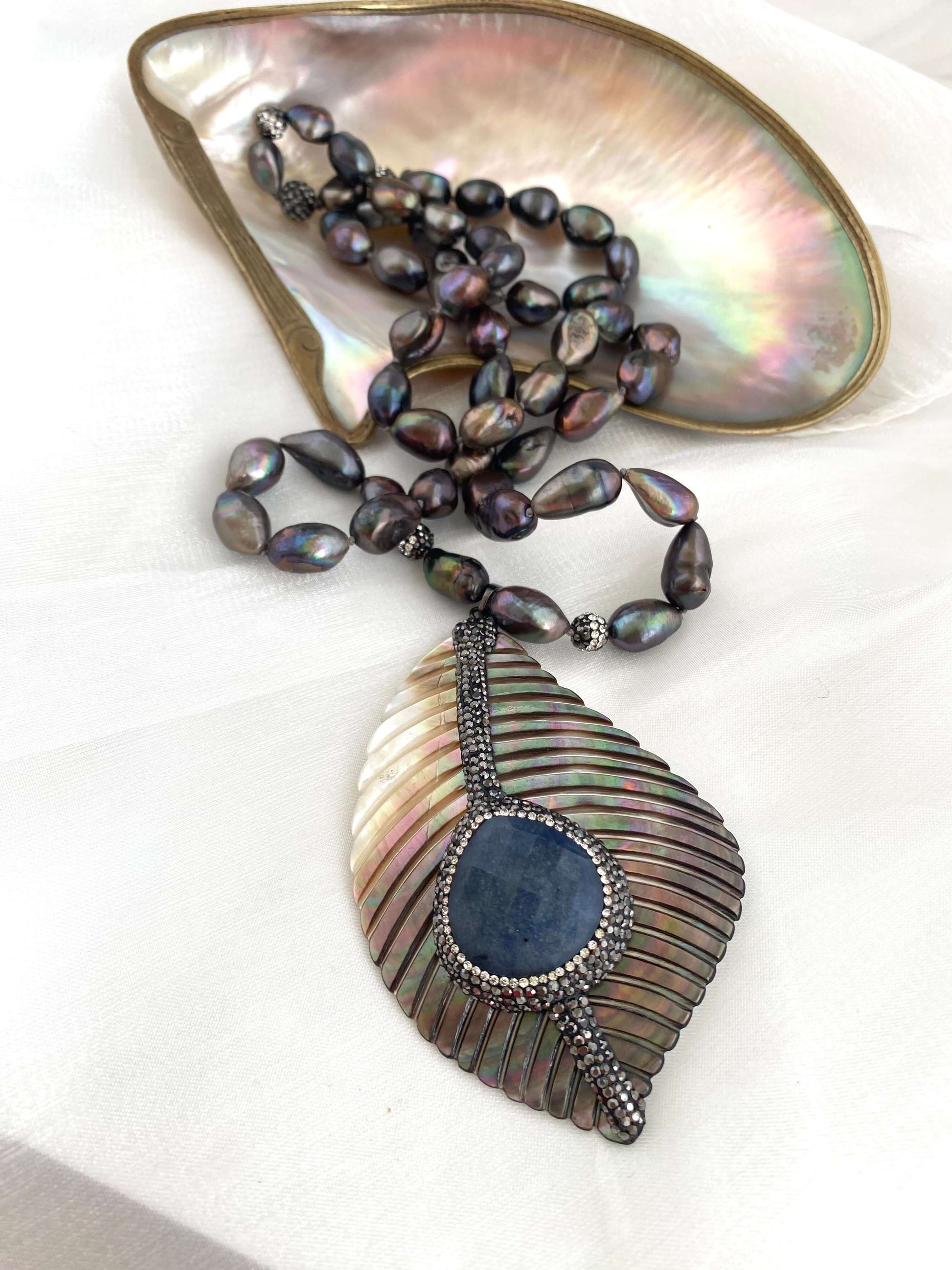 Long peacock black pearl necklace with abalone agate pendant displayed elegantly.