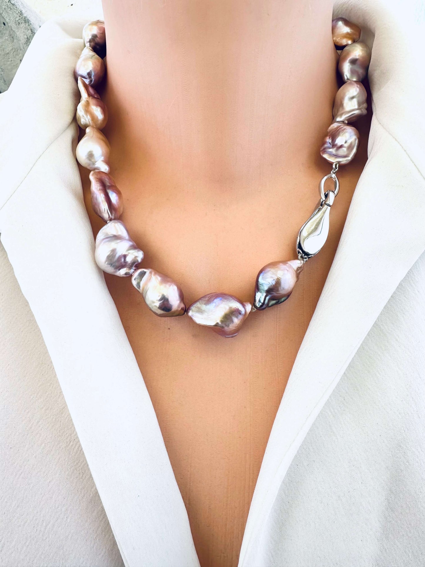 Pearl necklace worn by a person in a white outfit