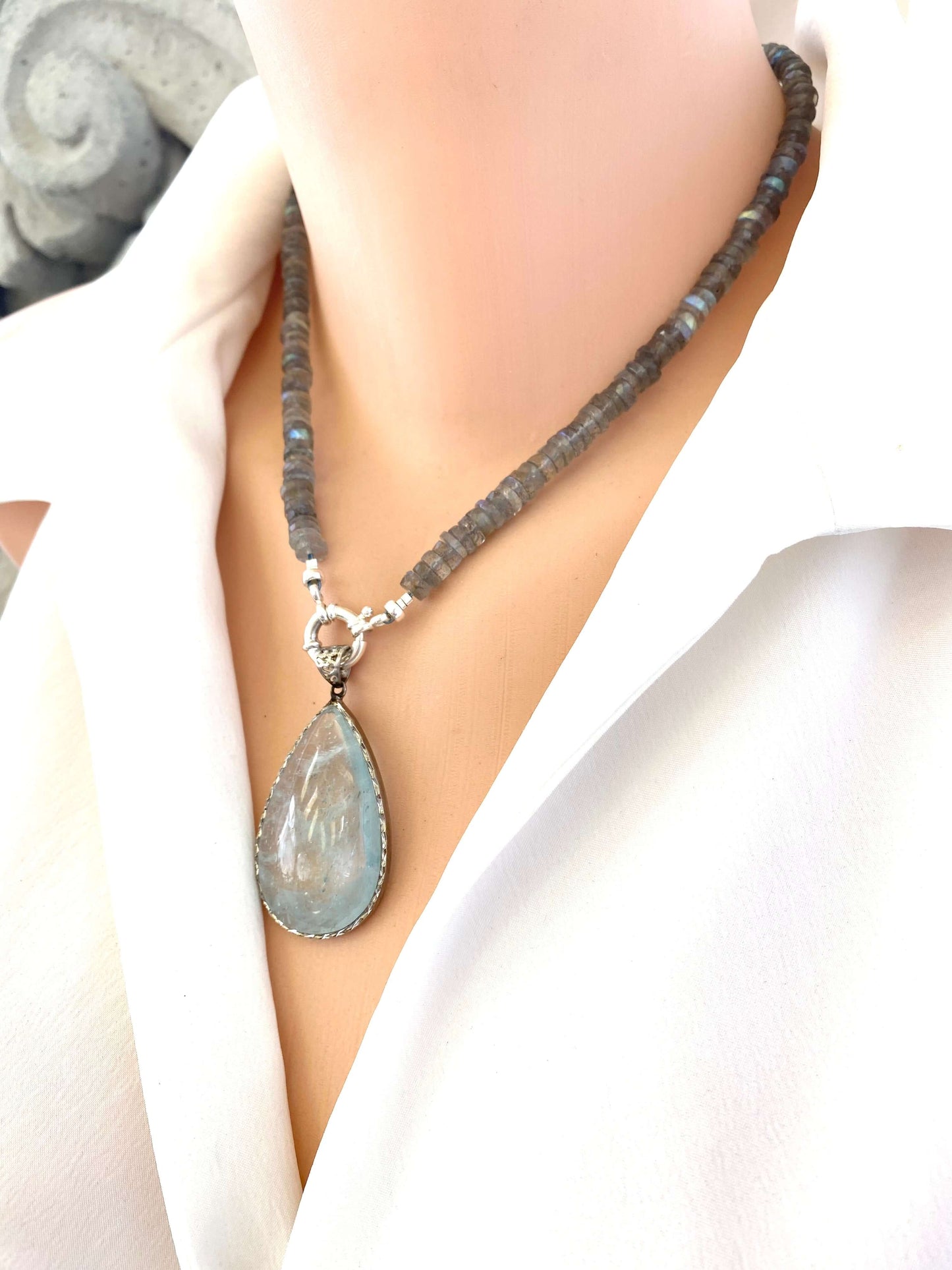Aquamarine teardrop pendant in oxidized sterling silver worn on a short necklace, highlighting its blue tones and artisan design.