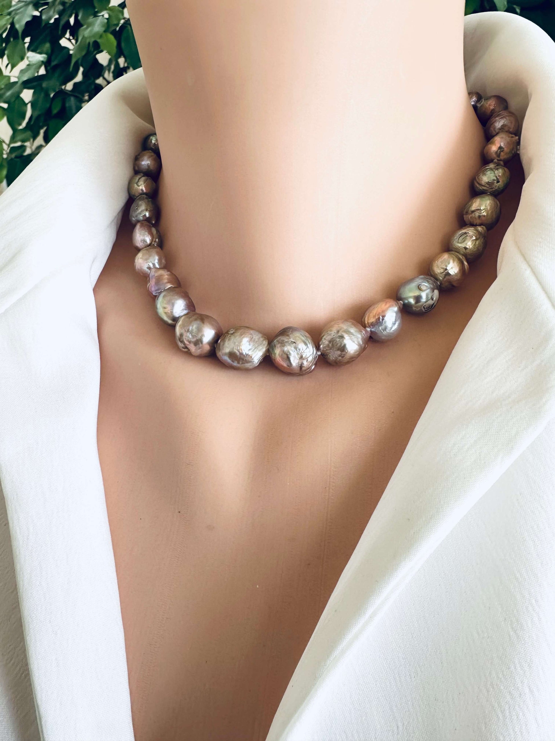 Edison pearl necklace with magnetic clasp worn at neckline showing metallic pink green lustre