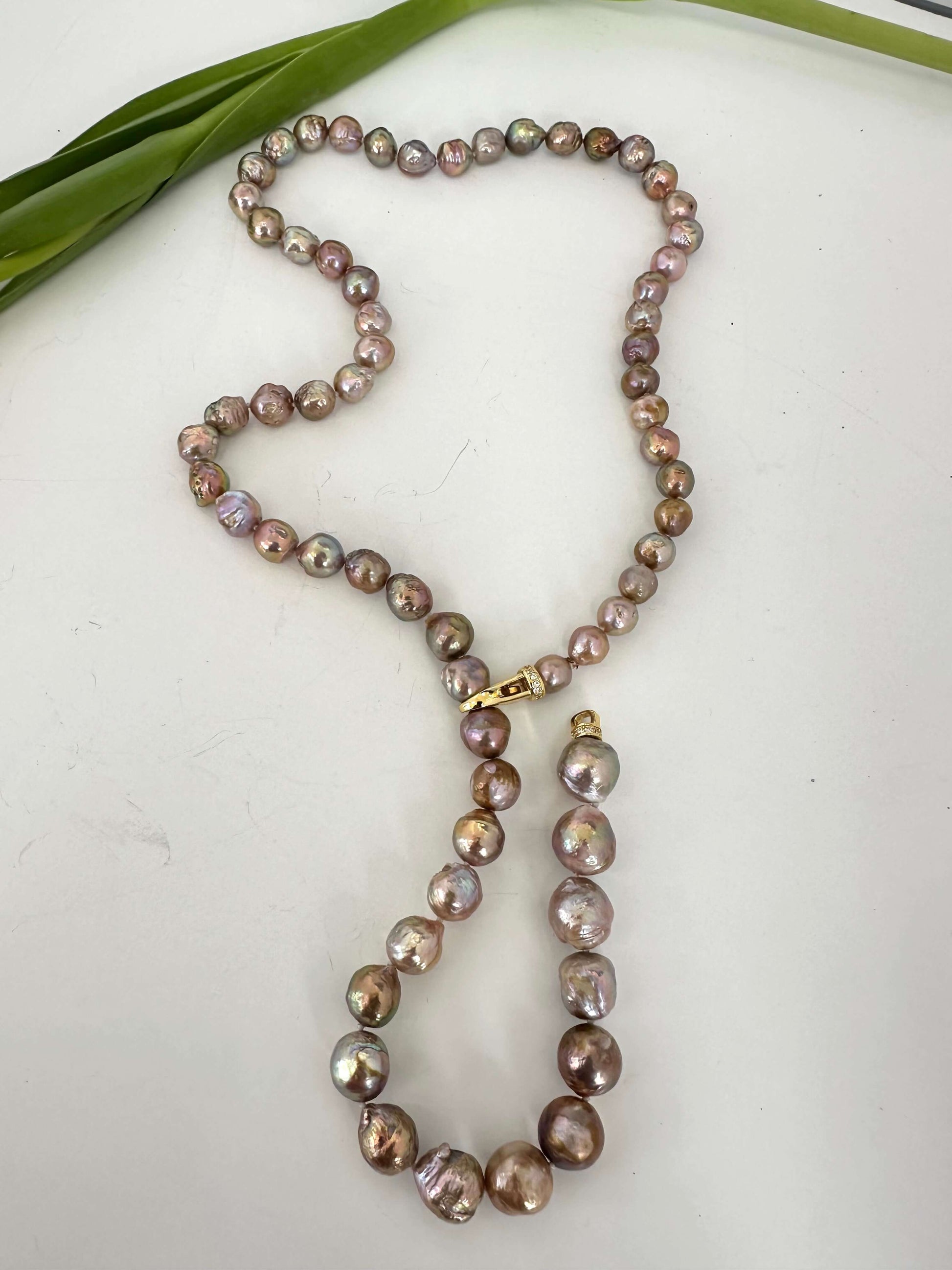 Convertible pink Edison baroque pearl necklace styled in Y shape on surface
